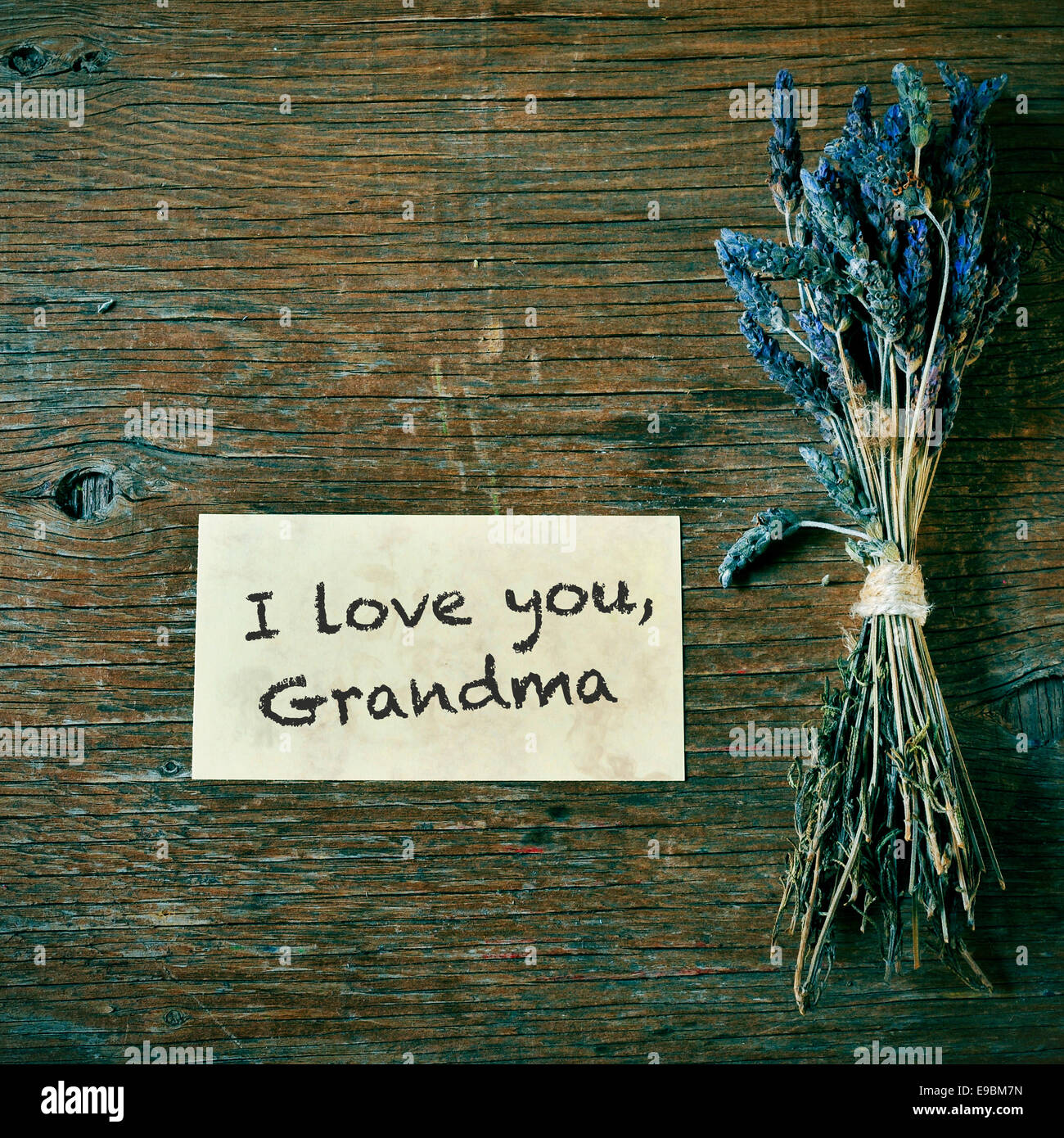 eine Handvoll Lavendelblüten und einen Zettel mit dem Text ich liebe dich, Oma auf einem Holztisch Stockfoto
