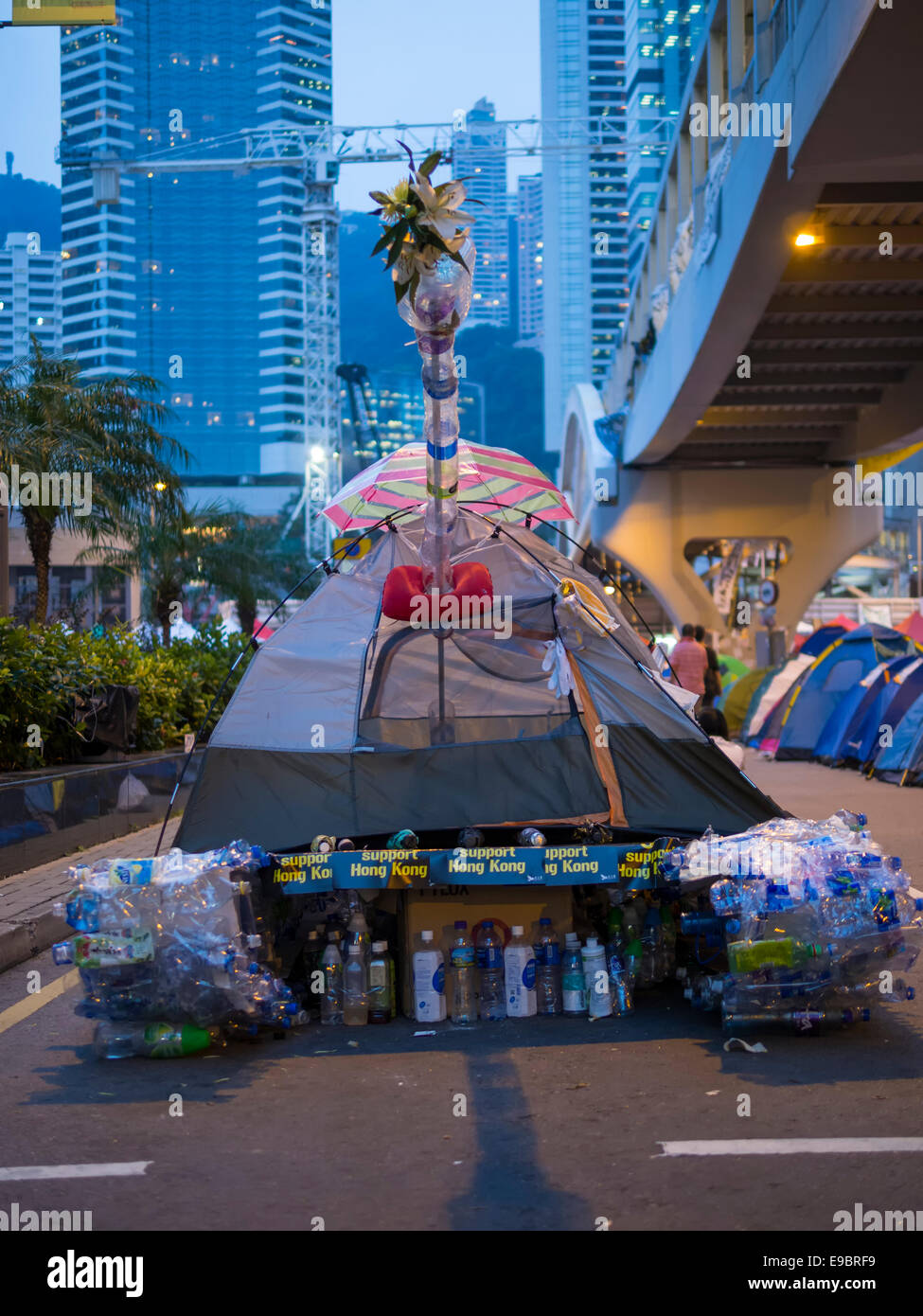 Hong Kong. 24. Oktober 2014. Studenten, pro-Demokratie-Aktivisten und anderen Unterstützern der Occupy Central, jetzt genannt den Regenschirm-Bewegung oder den Regenschirm-Revolution bleiben der Tamar Protest-Webseite auch als Sonnenschirm quadratisch oder Regenschirm Plaza. Ein Künstler, der Tiananmen-Platz teilgenommen hat einen Panzer aus einem Zelt und recycelten Wasserflaschen geschaffen. Stockfoto