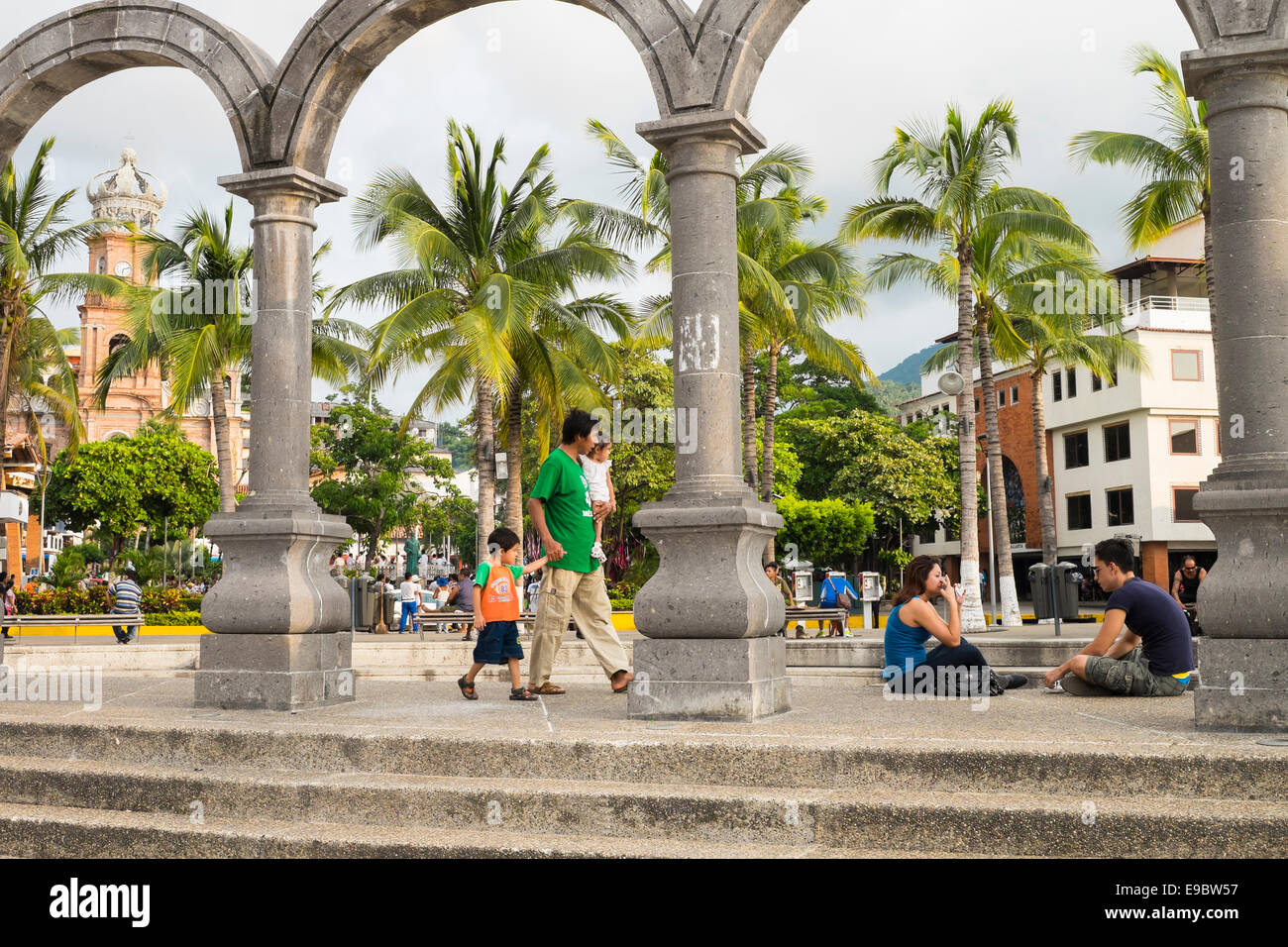 El Centro - Innenstadt von Puerto Vallarta mit Menschen in Los Arcos Bögen und Kirche von Nuestra Señora de Guadalupe im Hintergrund Stockfoto
