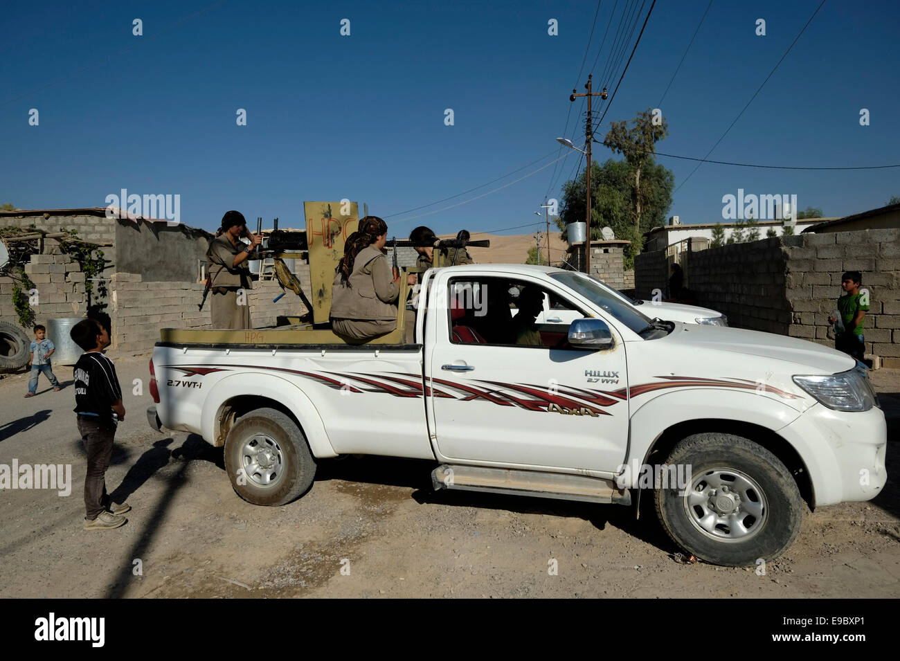 Weibliche kurdische Kämpfer der Einheiten der Freien Frauen verkürzt als YJA STAR militärischen Flügel der Frauen der Kurdischen Arbeiterpartei PKK mit einem DShK Heavy Machine Gun Offener-ziviler Pickup Truck patrouillieren in der Stadt Makhmur im Nordirak unterstützt montiert Stockfoto