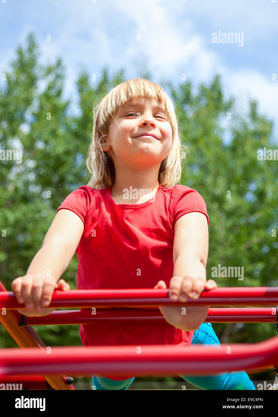 Niedliche kleine Mädchen posiert auf Klettergerüst Stockfoto