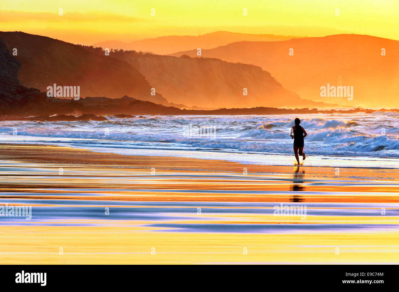 Person, die am Strand bei Sonnenuntergang Stockfoto