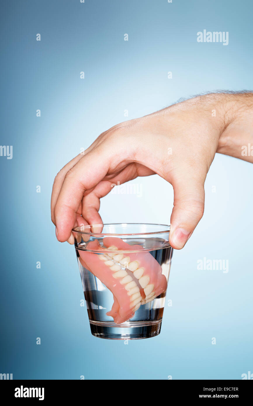 Mann hält ein Glas mit alten Zahnersatz. Stockfoto