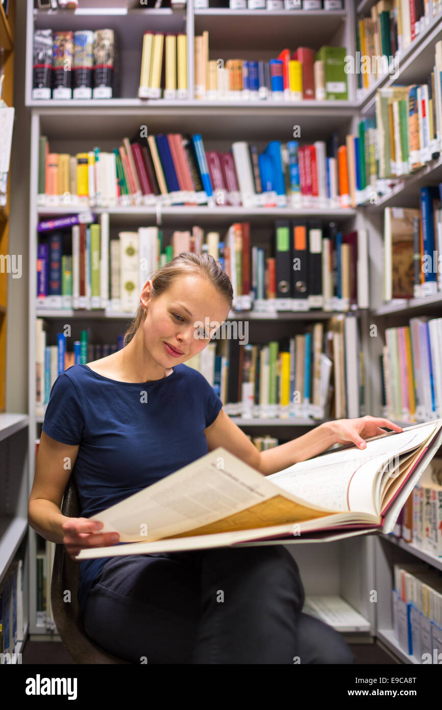 Hübsche, junge Frau, die ein altes Buch in Archiven zu studieren Stockfoto