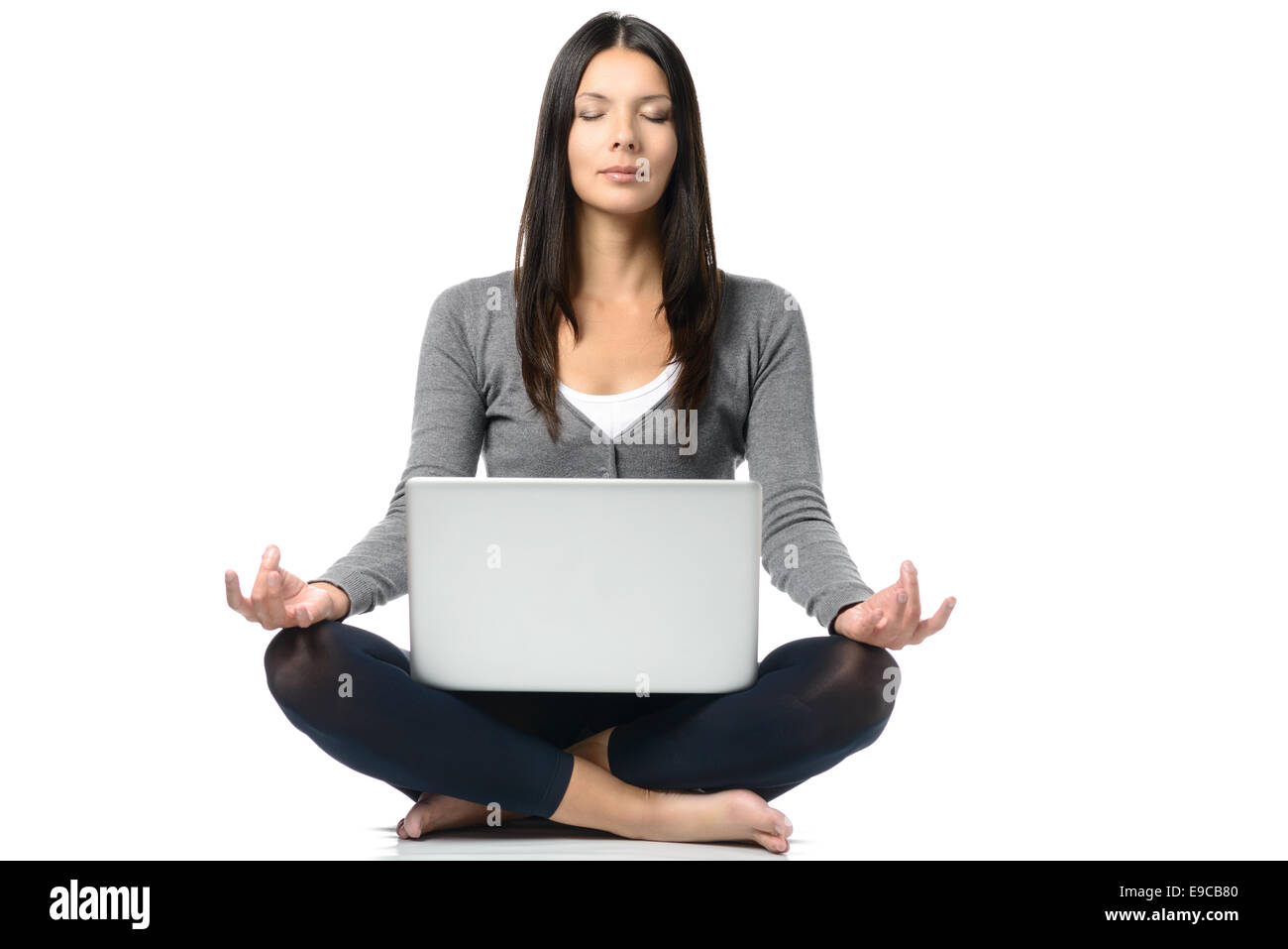 Ziemlich lange Haare Frau in Pose mit gekreuzten Beinen während vor einem Laptop vor zu meditieren. Isolated on White Stockfoto