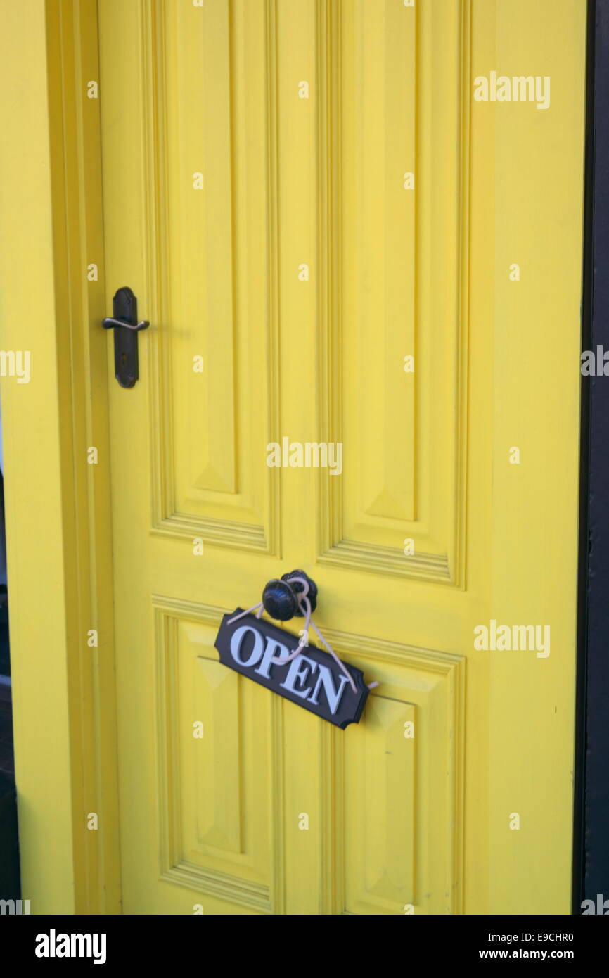 Schuss von einer gelben Fronttür mit Schild "geöffnet" Stockfoto