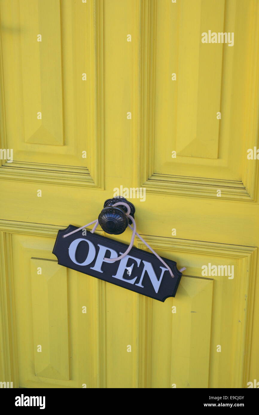 Schuss von einer gelben Fronttür mit Schild "geöffnet" Stockfoto