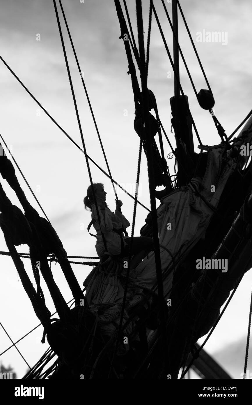 Junge Frau Klettern in der Takelage eines großen Schiffes. Stockfoto