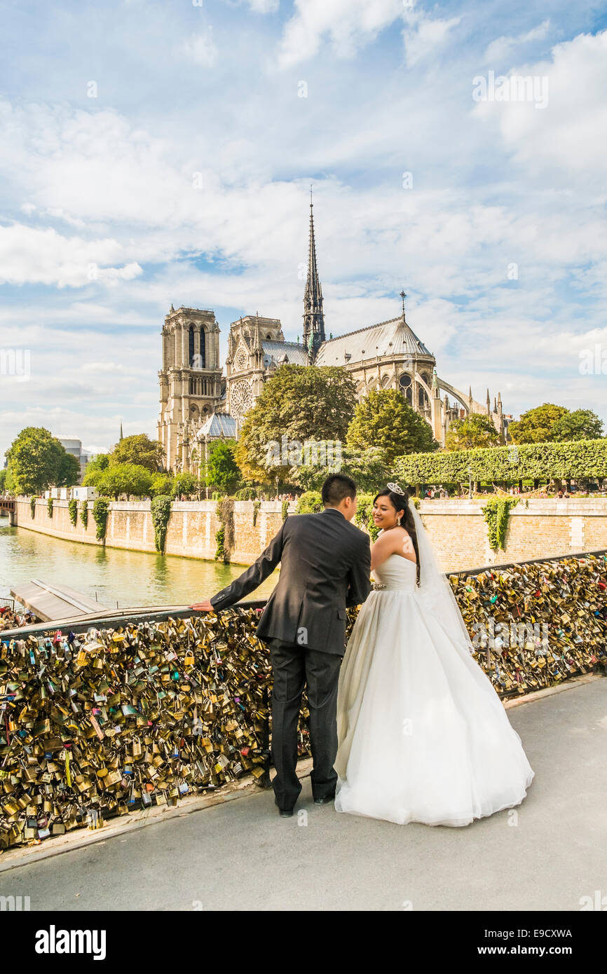 asiatische Braut und Bräutigam posiert auf Pont de L´archeveche mit Kathedrale Notre-Dame im Hintergrund, Paris, Ile de France, Frankreich Stockfoto