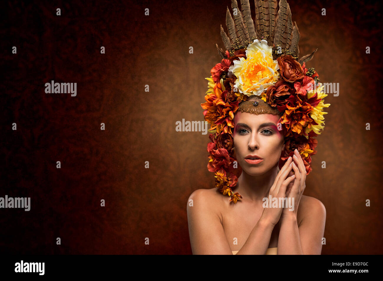 Schöne Frau mit Kopfbedeckung aus Blumen und Federn hergestellt Stockfoto