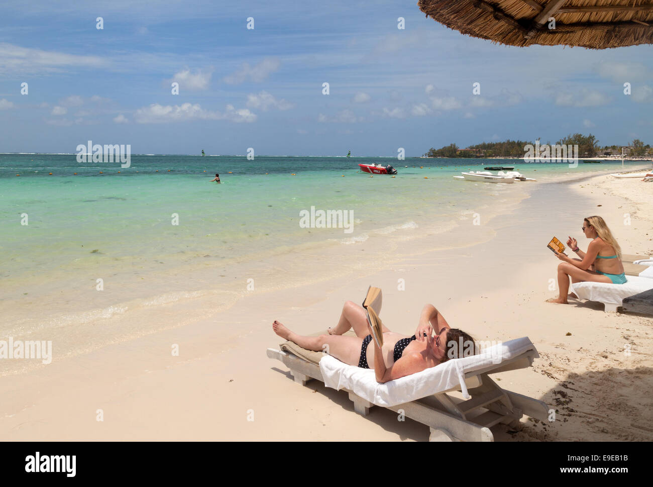 Frauen lesen am Strand im Urlaub, Belle Mare Beach, Ostküste Mauritius Stockfoto