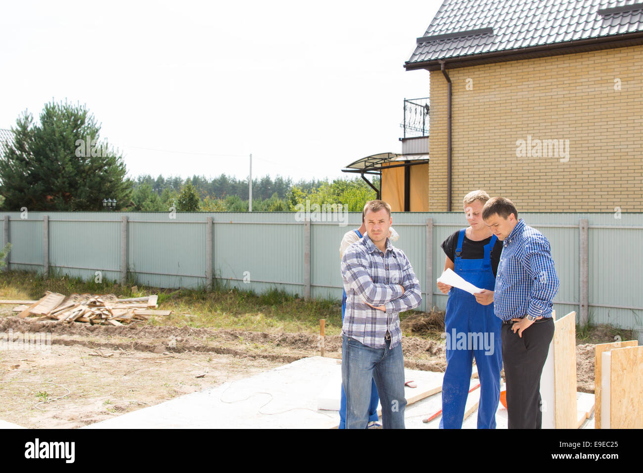Gruppe von Bauherren und Website Ingenieure stehen diskutieren Details auf einem geräumten Wohn-Grundstück auf der Grundlage eines neuen Hauses Stockfoto