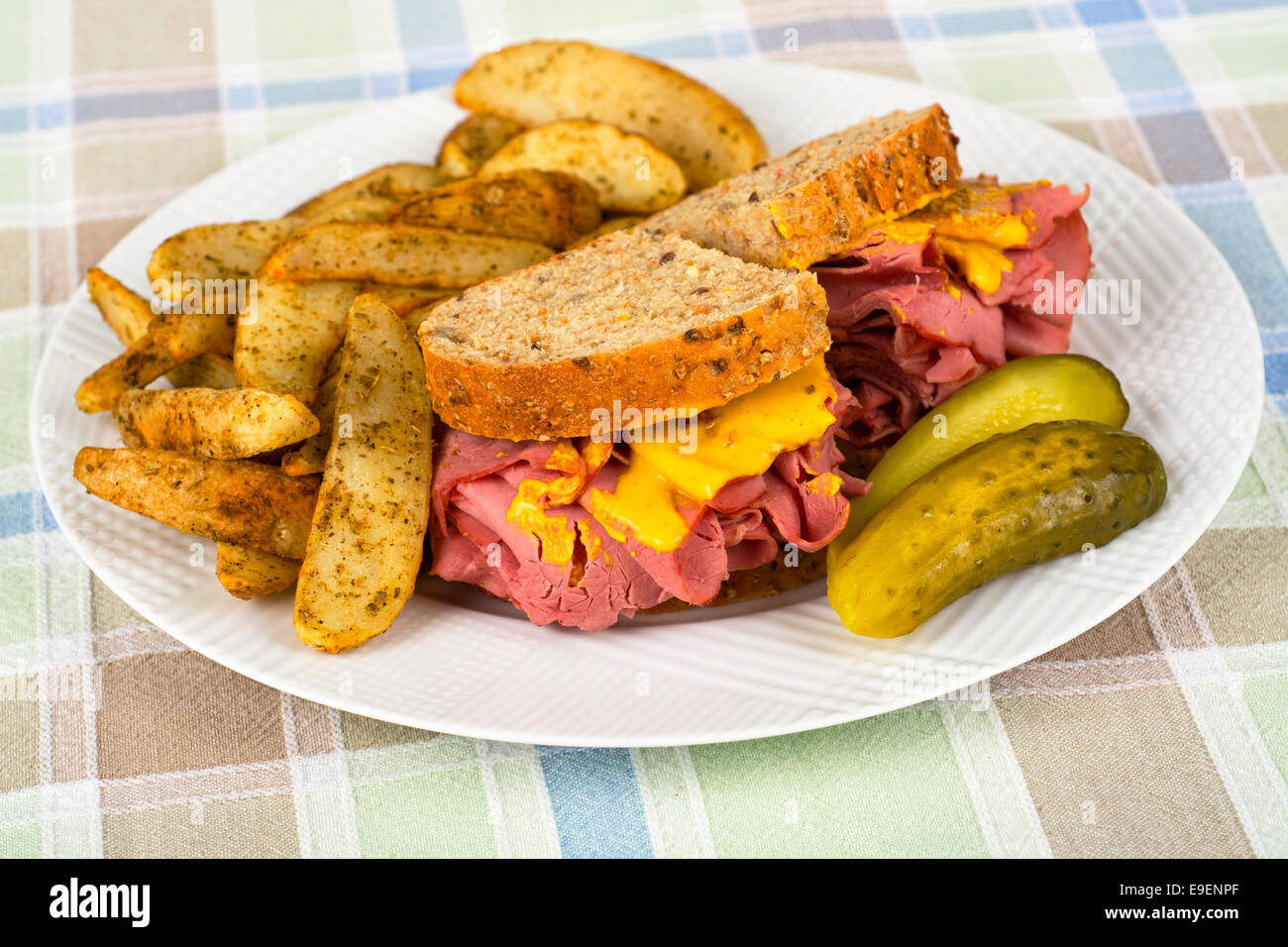 Corned Beef Sandwich Senf gebraten, Kartoffeln und Gurke auf Platte Stockfoto