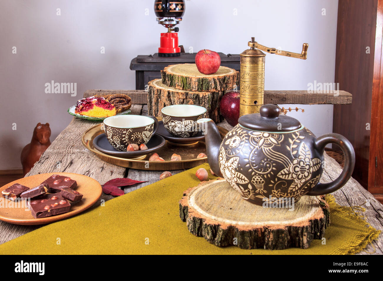 Tassen Tee auf alten Holztisch mit Äpfeln, Nüssen, Würfel von Schokolade und Tee Topf neben ihnen im Herbst Dekoration Stockfoto