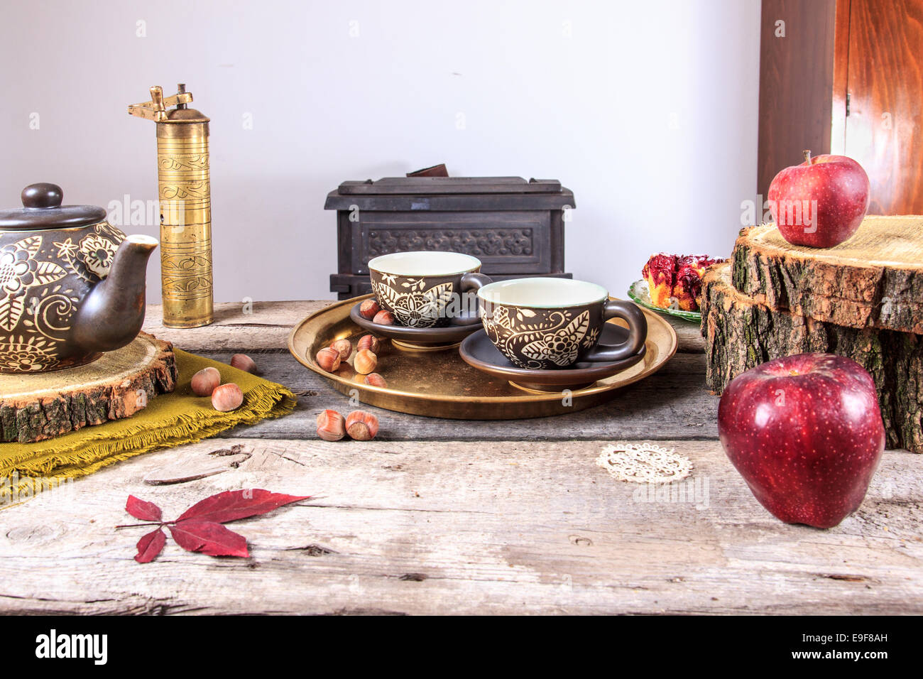 Tassen Tee auf alten Holztisch mit Äpfeln, Nüssen und Teekanne neben ihnen. Stockfoto