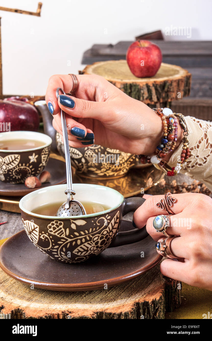 Retro- und Vintage weiblichen Hand gerührt und drückte in einer Tasse Tee pflanzliche Zutat, alten Herbst Dekoration Stockfoto