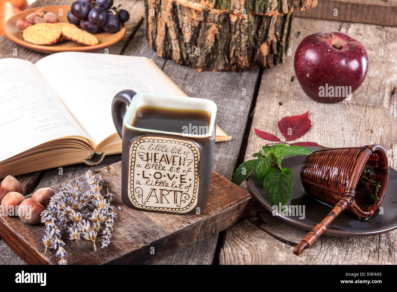 interessante Tasse Tee mit Nachricht auf einem Holztisch mit einem Sieb auf einem Teller neben Cup und offene alte Buch, Herbst Dekorati Stockfoto