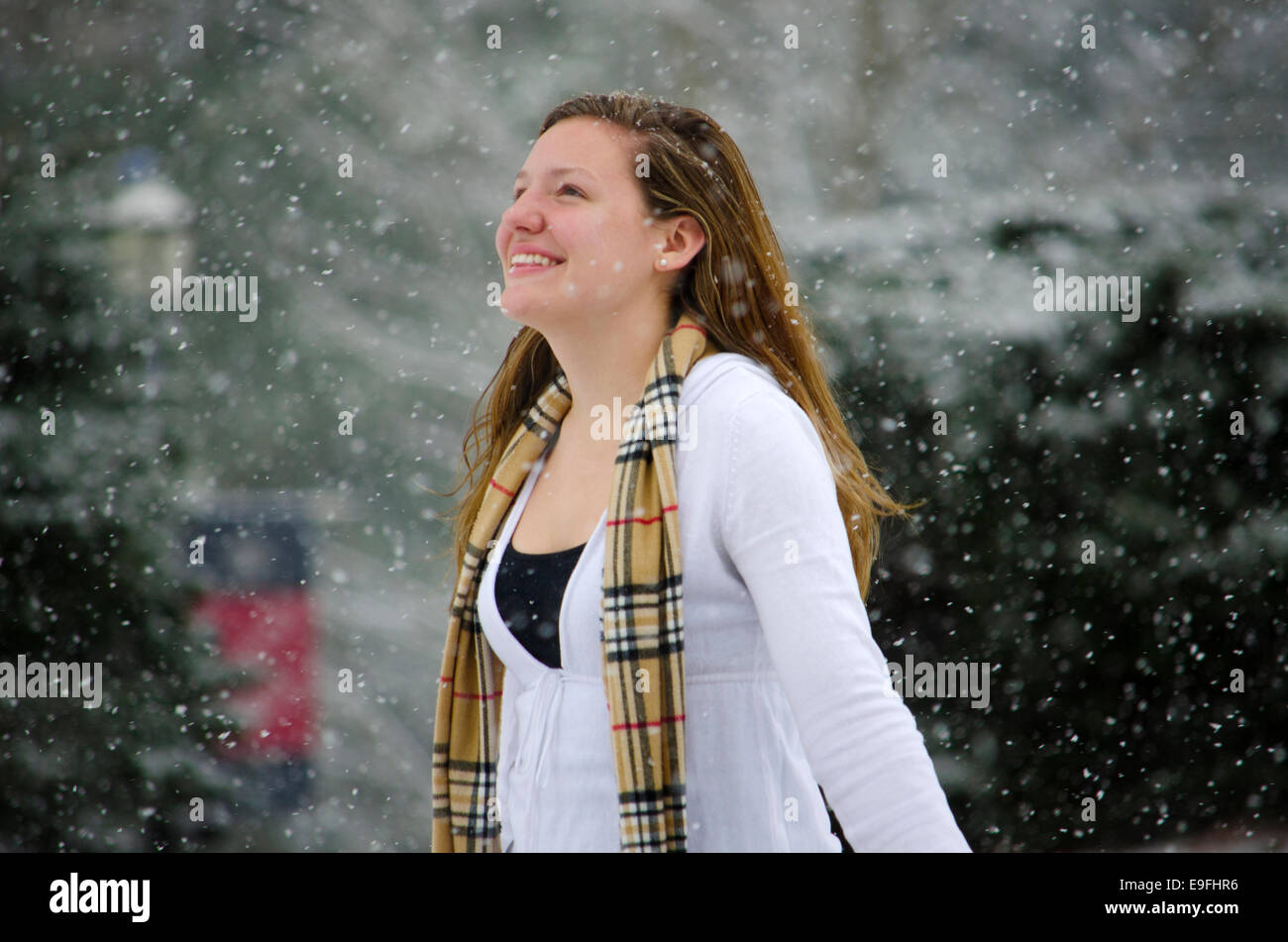 Leise rieselt der Schnee: eine junge Frau wirft ihre Arme Sieg einer schönen Schnee-Dusche. Stockfoto