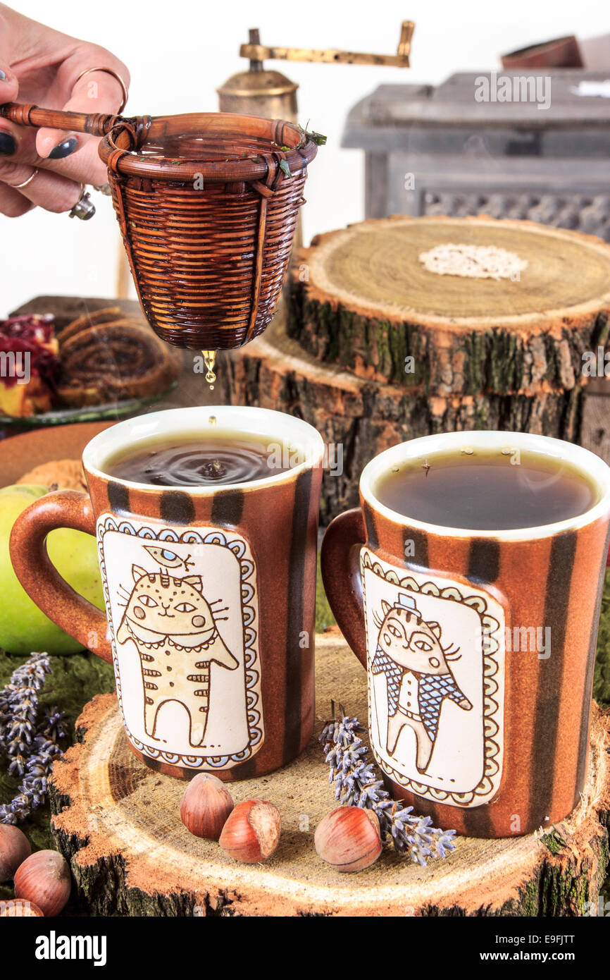 aus den Wasserkocher für Tee Gießen durch ein Sieb, in zwei Tassen Tee, einen angenehmen Herbst Dekoration mit Obst und Kuchen Stockfoto