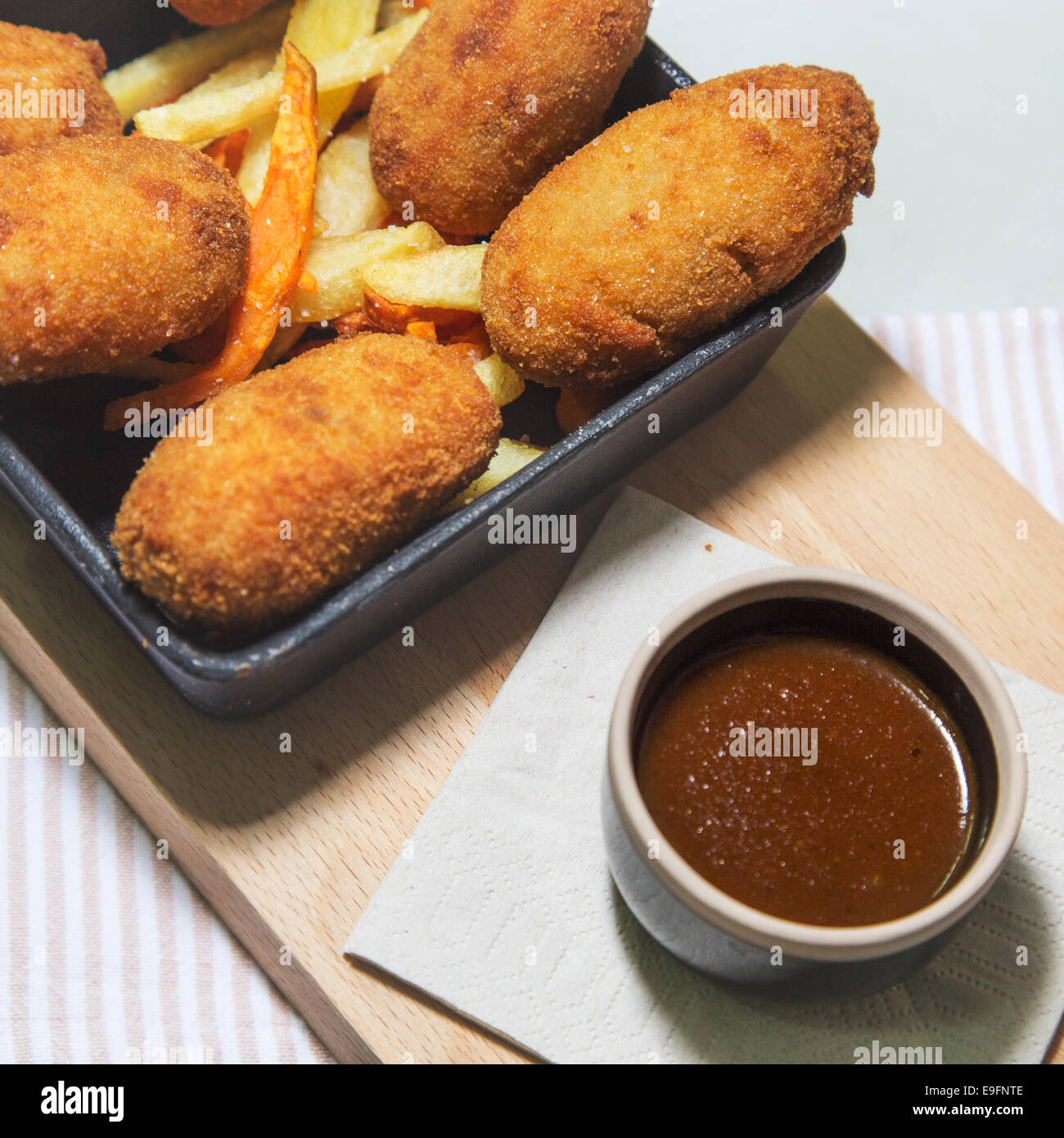 High End Essen Goldene Kroketten In Einem Bett Von Kartoffel Chips Serviert In Einer Schwarzen Kugel Mit q Sauce In Ein Schneidbrett Aus Holz Stockfotografie Alamy