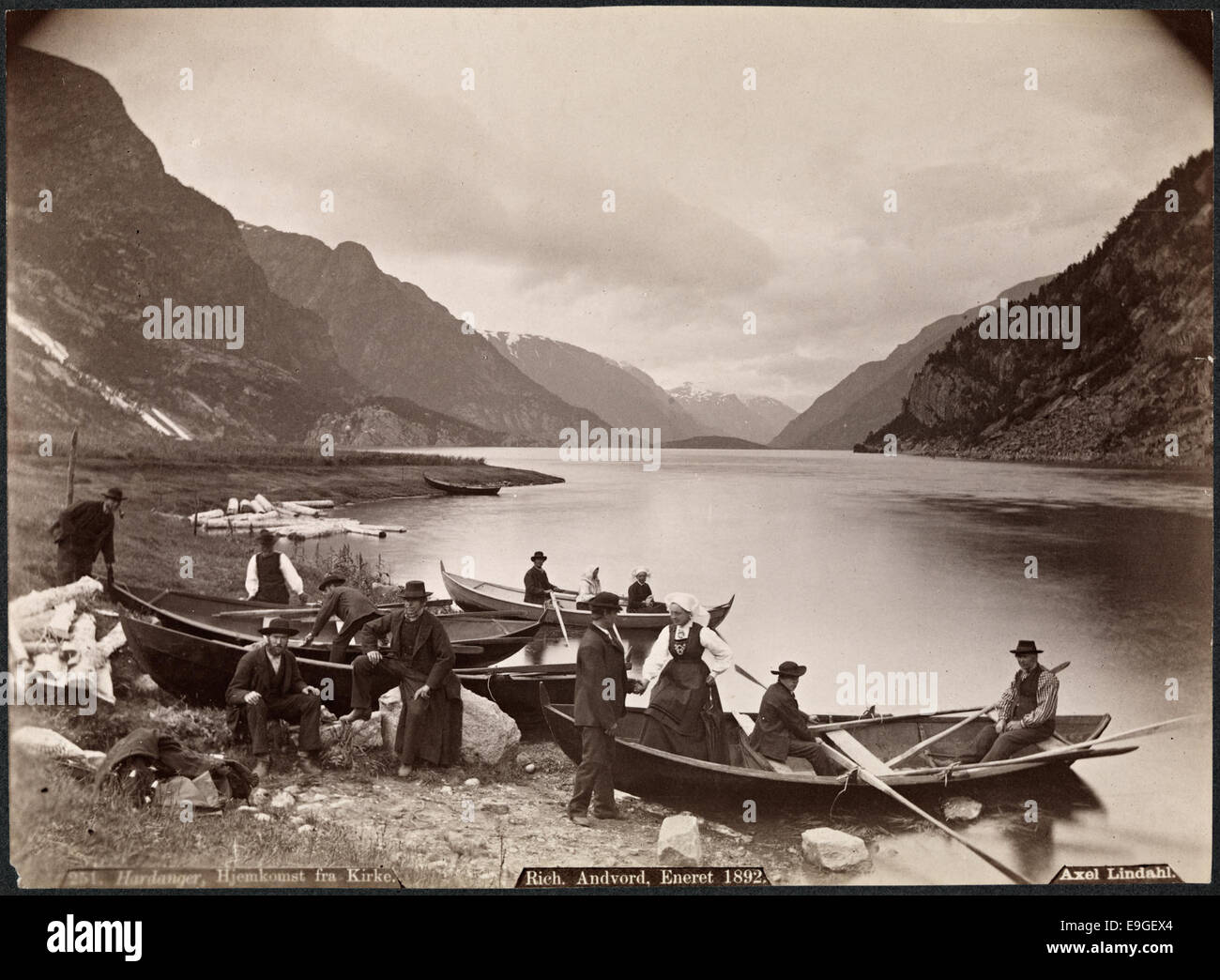 Ein Foto von der Rückkehr aus der Kirche in Hardanger, Norwegen, bei der eine Bootsprozession auf dem Fjord aufgenommen wurde. Das Bild zeigt Menschen in traditionellen norwegischen Nationalkostümen (Bunader), Männer und Frauen rudern in Booten vor der malerischen Kulisse der Hardanger-Region in Hordaland. Stockfoto