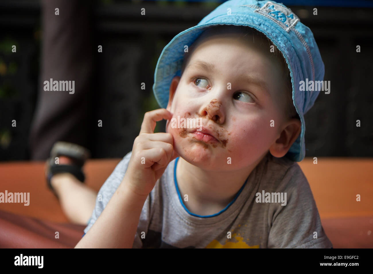 Nahaufnahme eines kleinen Jungen, Grübeln, verschmiert Gesicht mit Schokolade Stockfoto