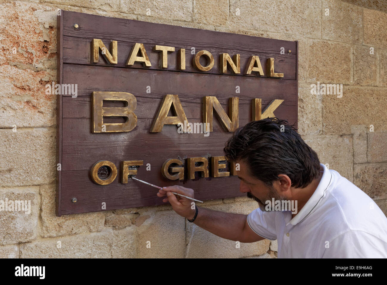 Melden Sie "National Bank of Greece", Mann, Malerei, die Zeichen, die neue Stadt, Rhodos, Insel Rhodos, Dodekanes, Griechenland Stockfoto