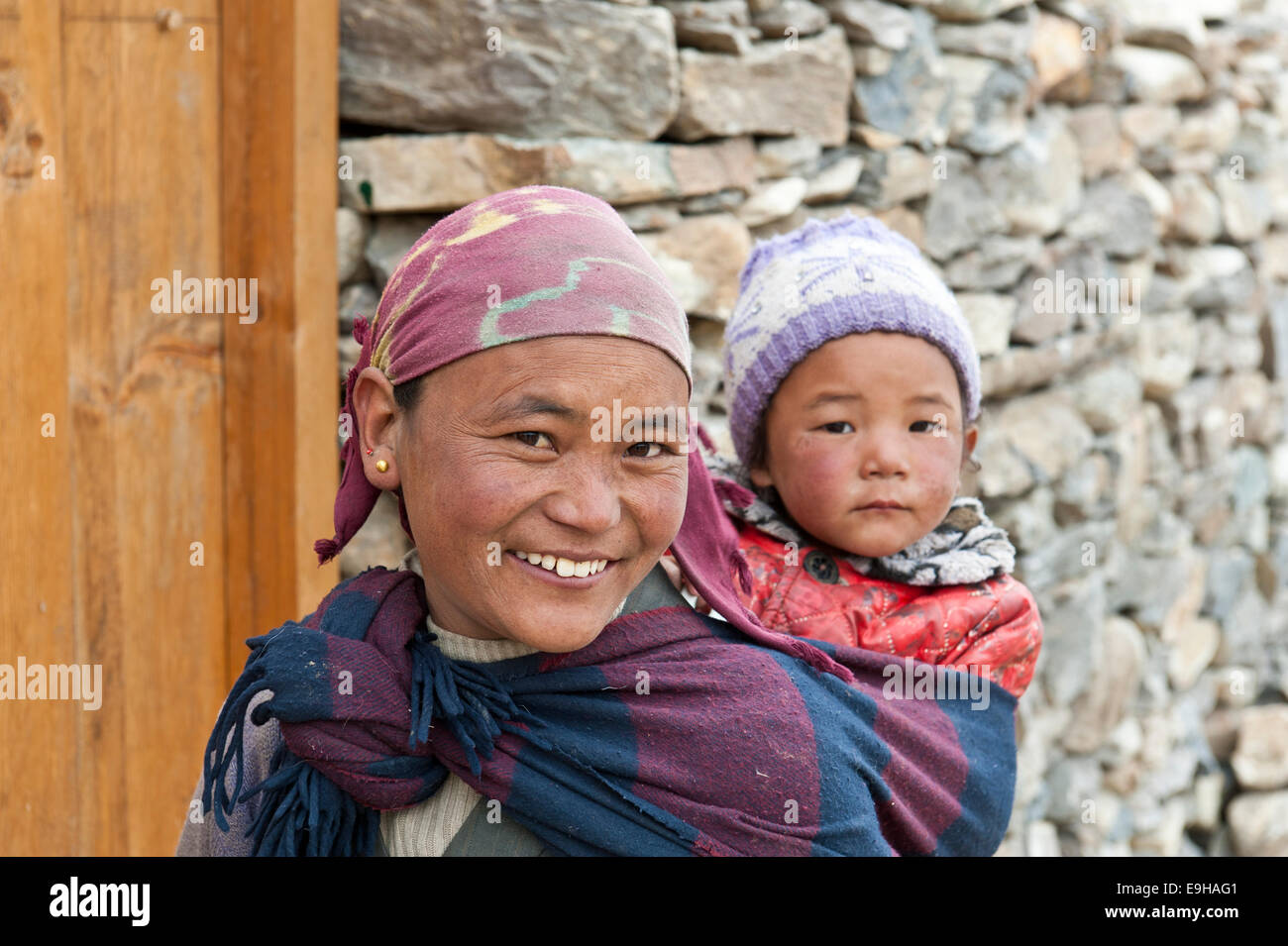 Lächelnde Frau mit einem Kind auf ihrem Rücken, die ethnische Gruppe der Lopa, Lo oder Mustang, Nepal Stockfoto