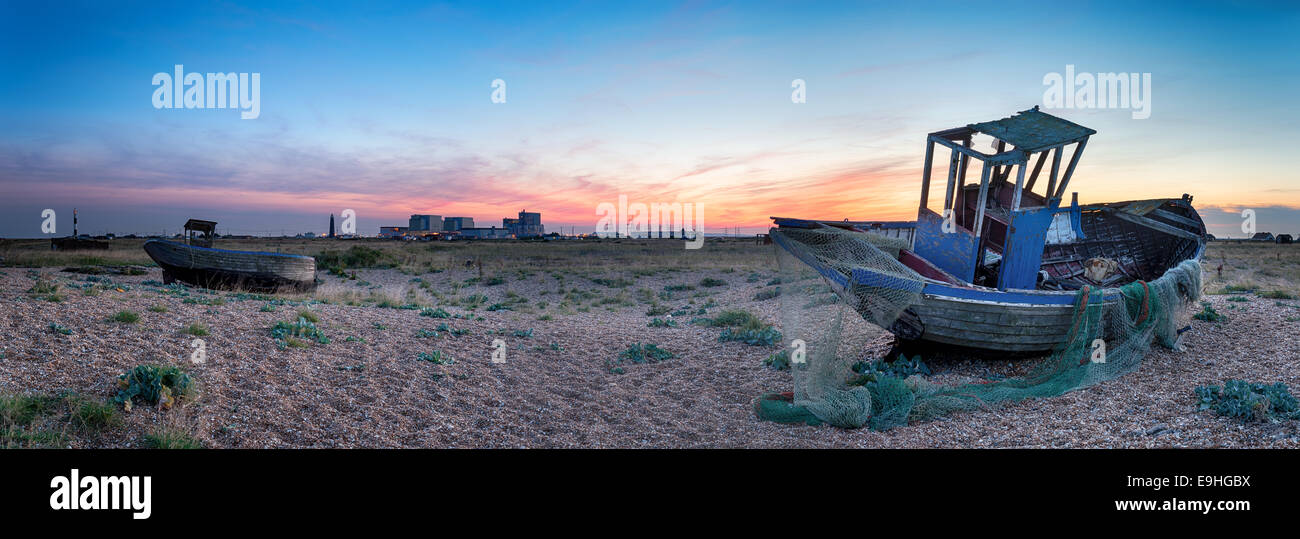 Ein altes zerstört Angelboote/Fischerboote bei Dungeness in Kent mit den zwei Leuchttürmen und Dungeness Kernkraftwerk im Hintergrund Stockfoto