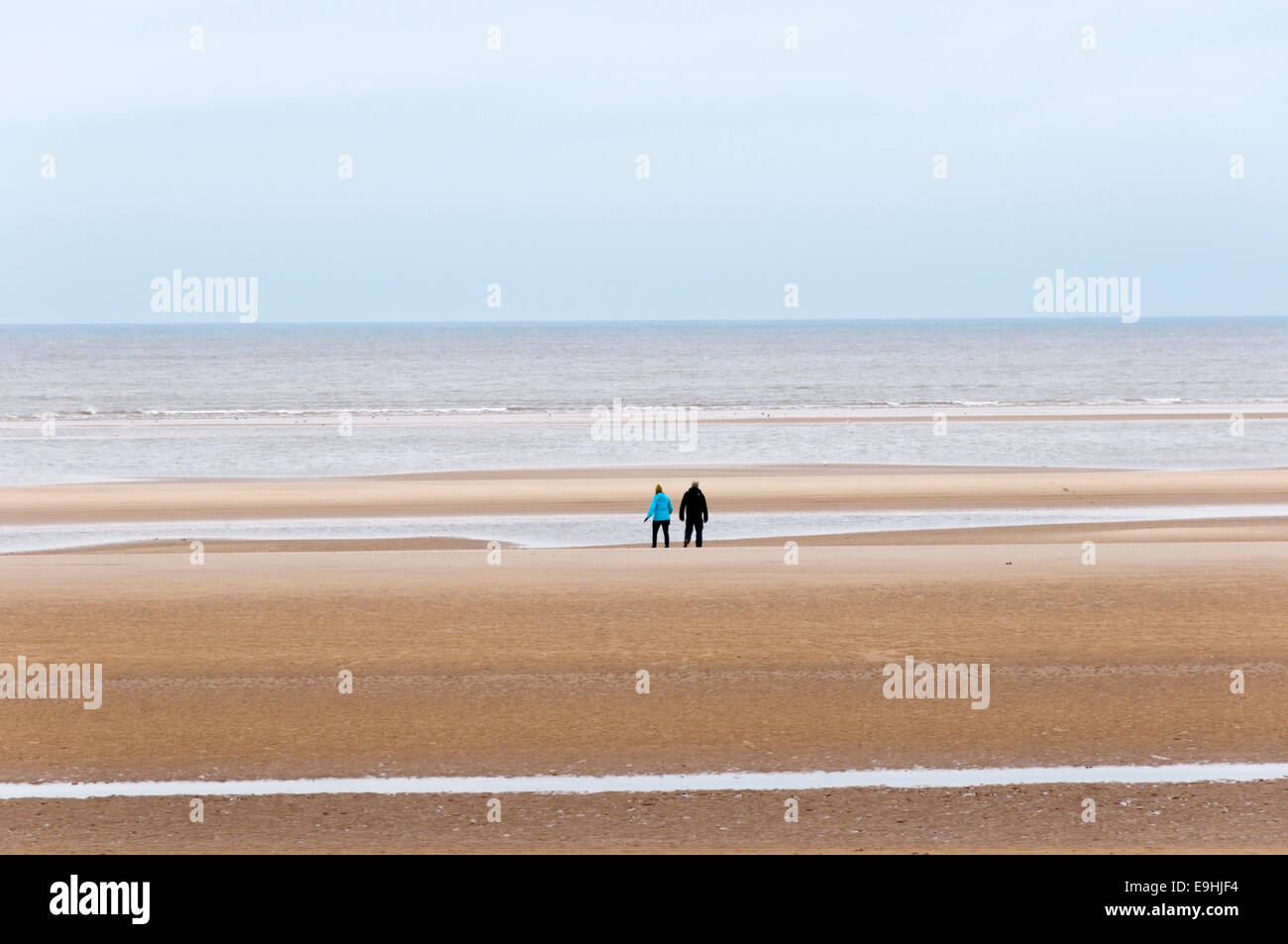 Paare, die am Strand von Norfolk zwischen Weihnachten und Neujahr. Stockfoto
