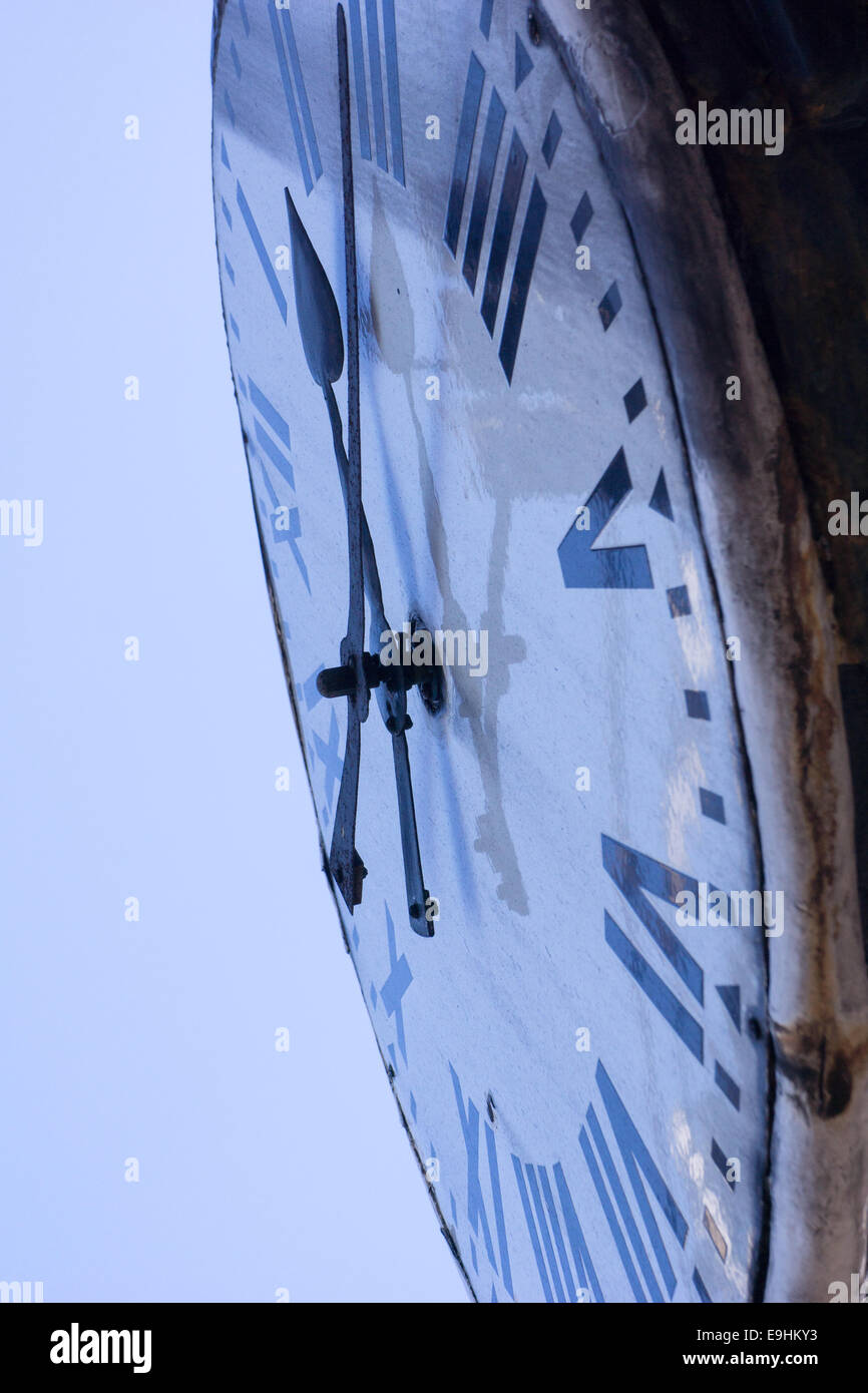 Zeit. Nahaufnahme eines alten Zifferblatts mit römischen Ziffern und verwitterten Metallkanten vor einem hellen Himmel. Stockfoto