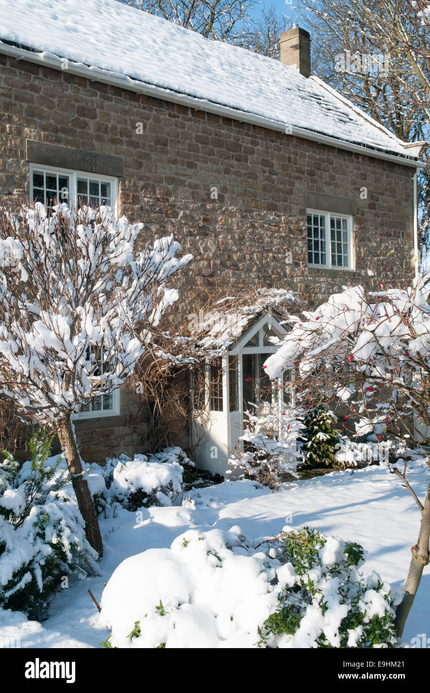 Schneebedeckte Landschaft in England. Schneebedecktes Steinhaus und Garten in Doncaster schaffen eine helle und friedliche Winterszene Stockfoto