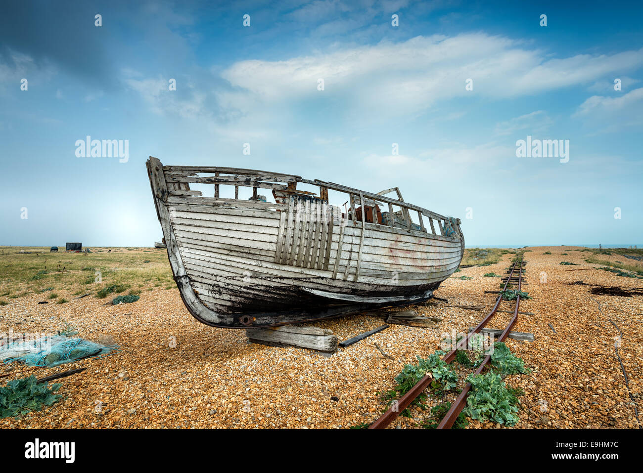 Einem alten Holzboot neben einer Bahntrasse auf einem Kiesstrand Stockfoto