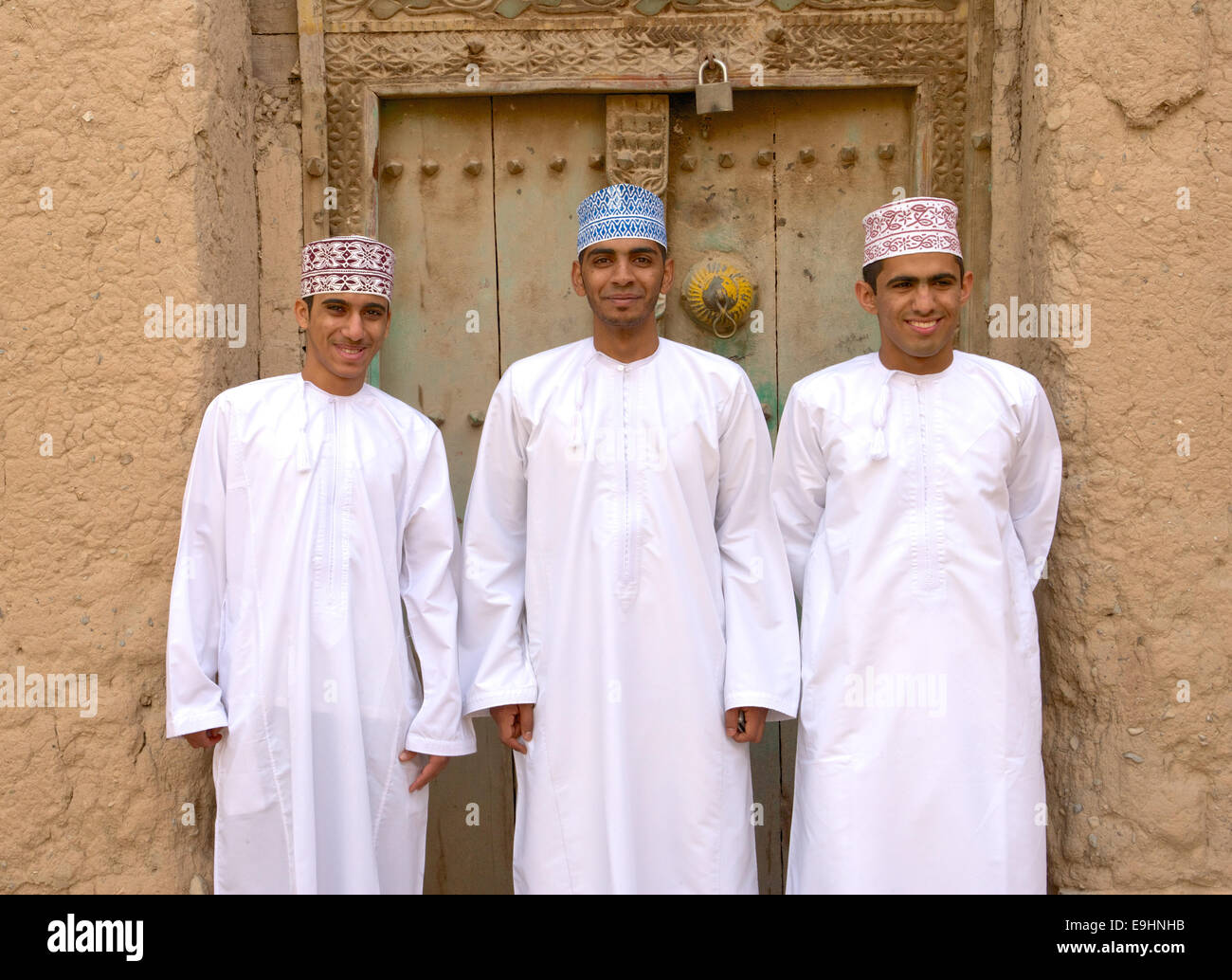 Drei junge omanischen Männer in traditioneller Kleidung bei den Ruinen von Birkat Al Mouz im Bereich Nizwa des Sultanats Oman. Stockfoto