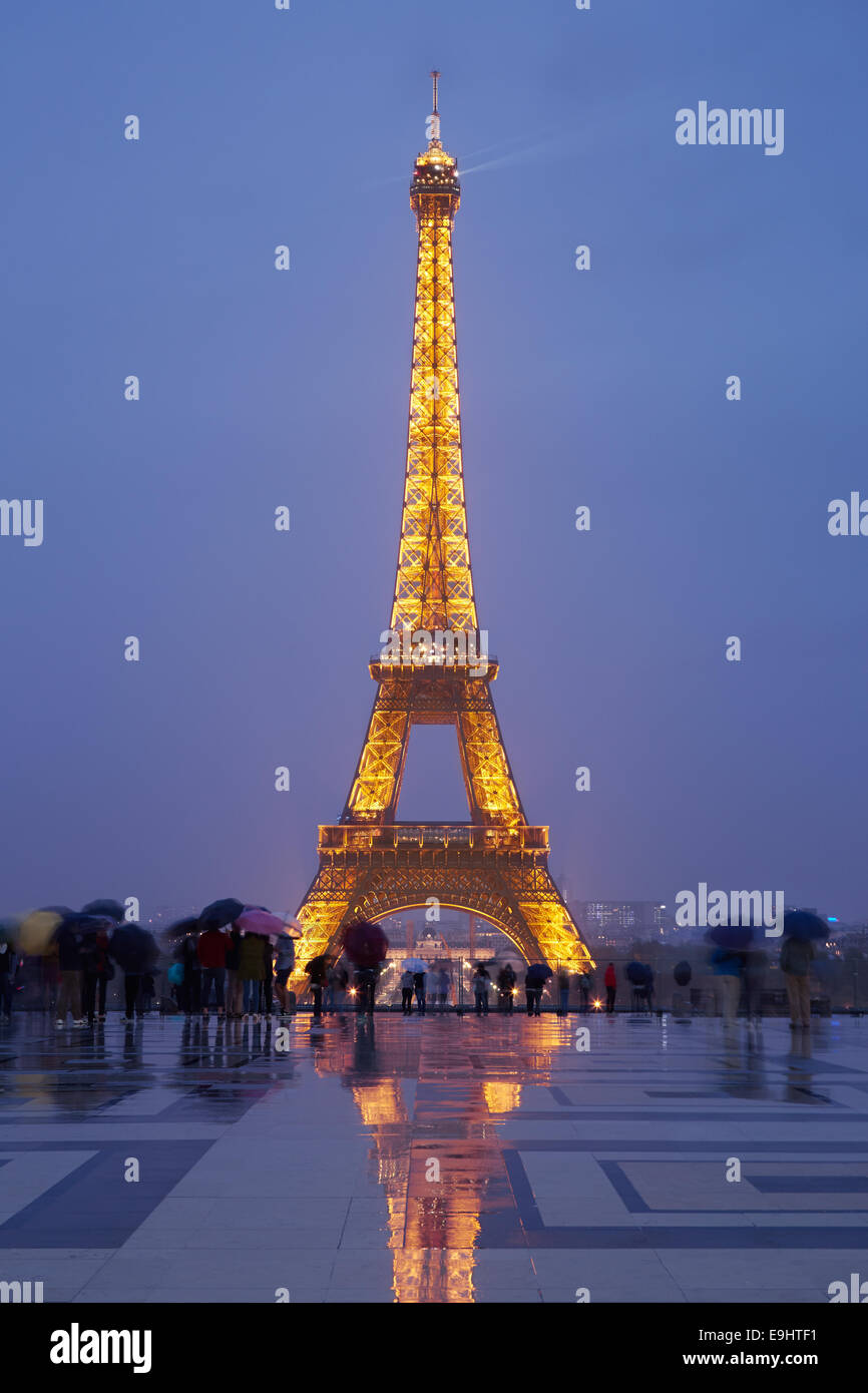 Eiffelturm in Paris mit Touristen in der Dämmerung, Regen Stockfoto
