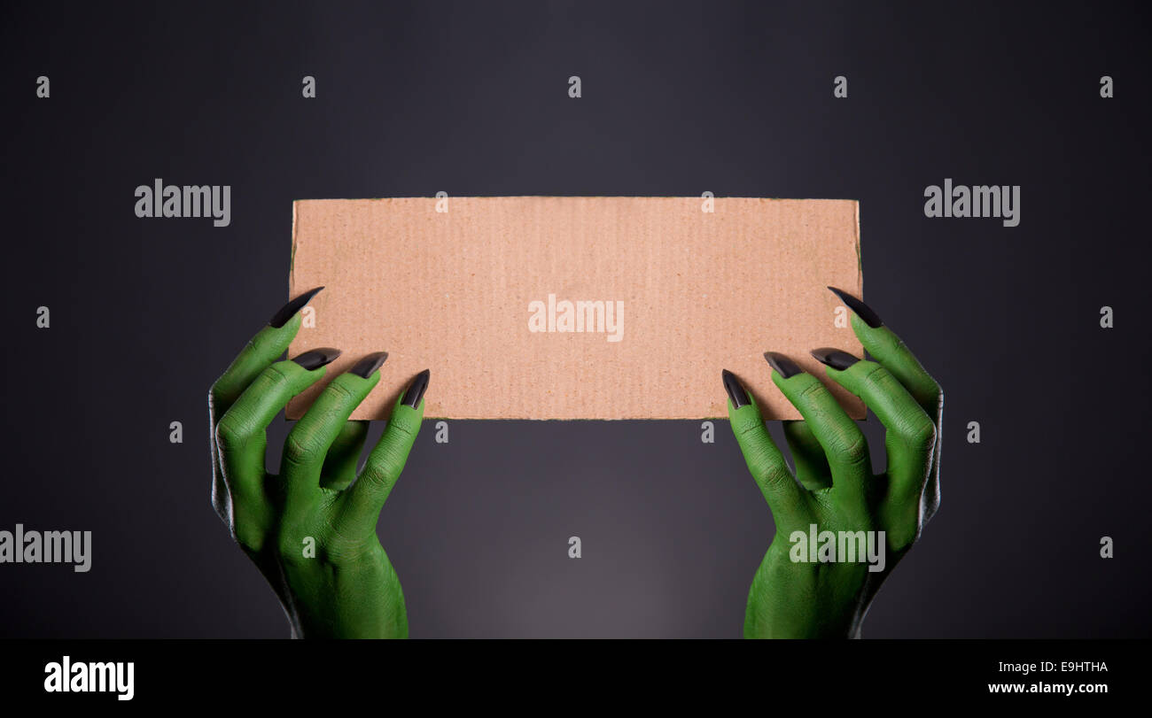 Grünes Monster Hände mit schwarzen Nägeln mit leeren Stück Pappe, Halloween-Thema Stockfoto