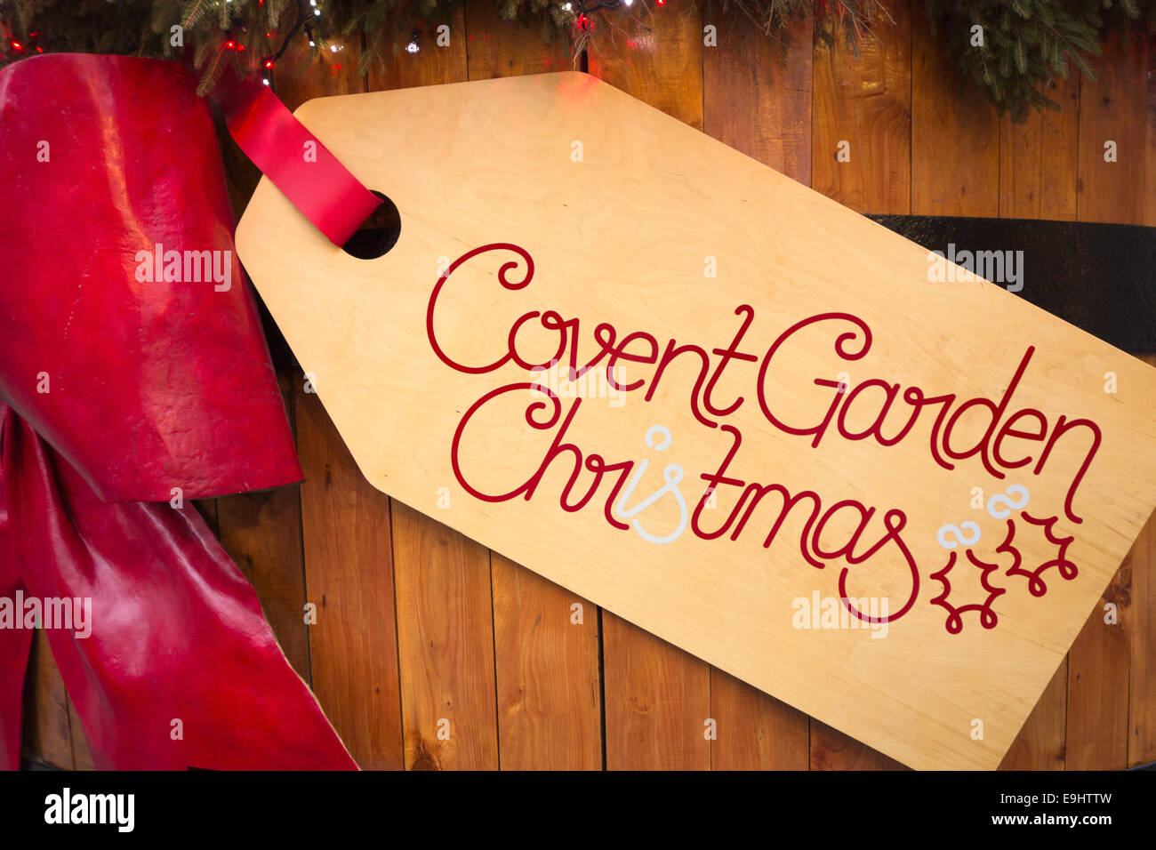 England, London, Covent Garden. Riesige hölzerne Label hängen von einer roten Schleife Werbung Weihnachten in Covent Garden Stockfoto
