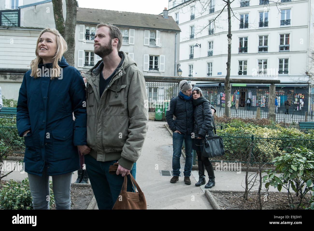 Zwei Paare stehen auf der Straße halten sich an den Händen und umarmen, während Sie an der Wand der Liebe Touristenattraktion in Paris. Stockfoto
