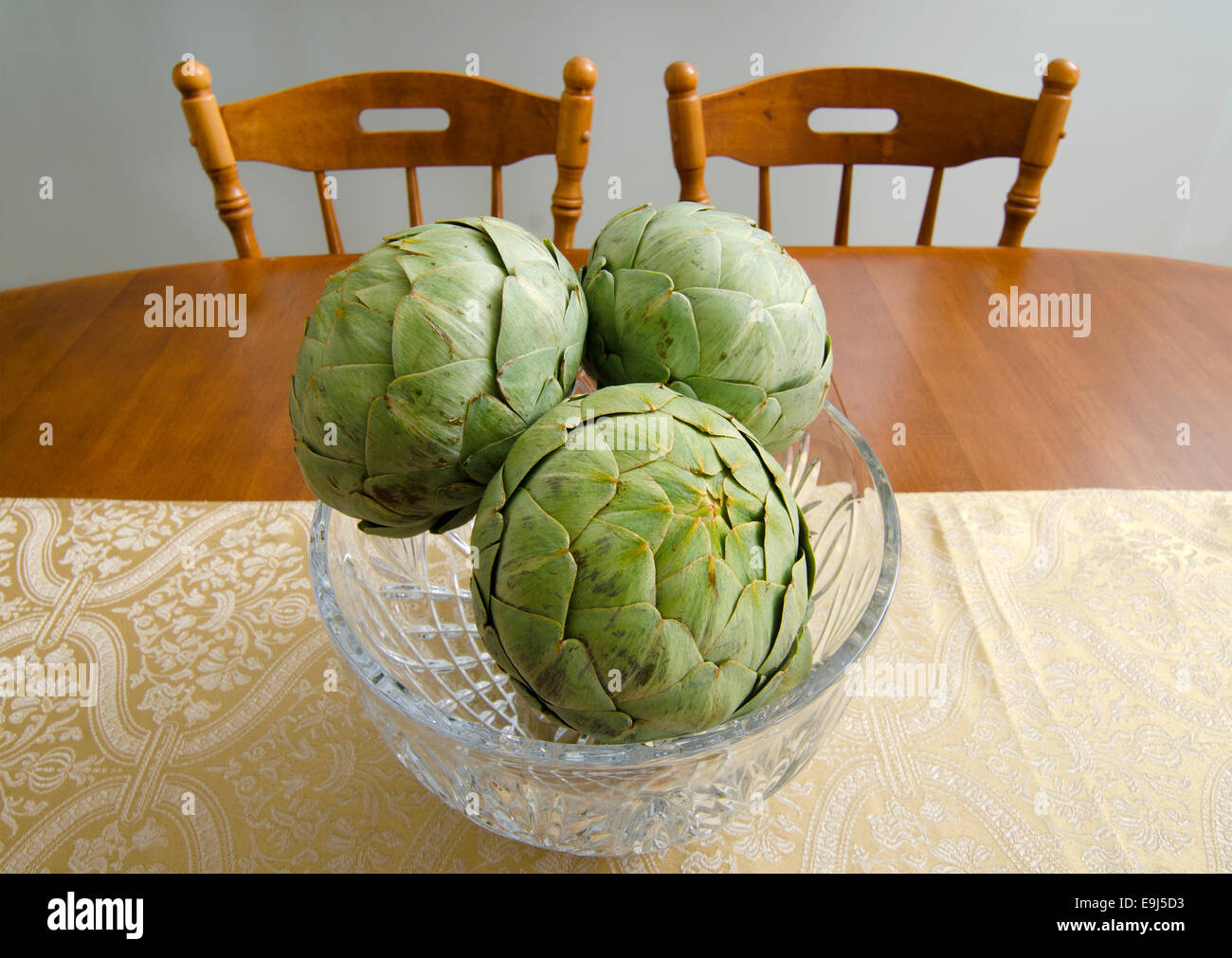 Artischocken in eine Glasschüssel schaffen ein dekoratives Mittelstück für einen Esstisch. Stockfoto