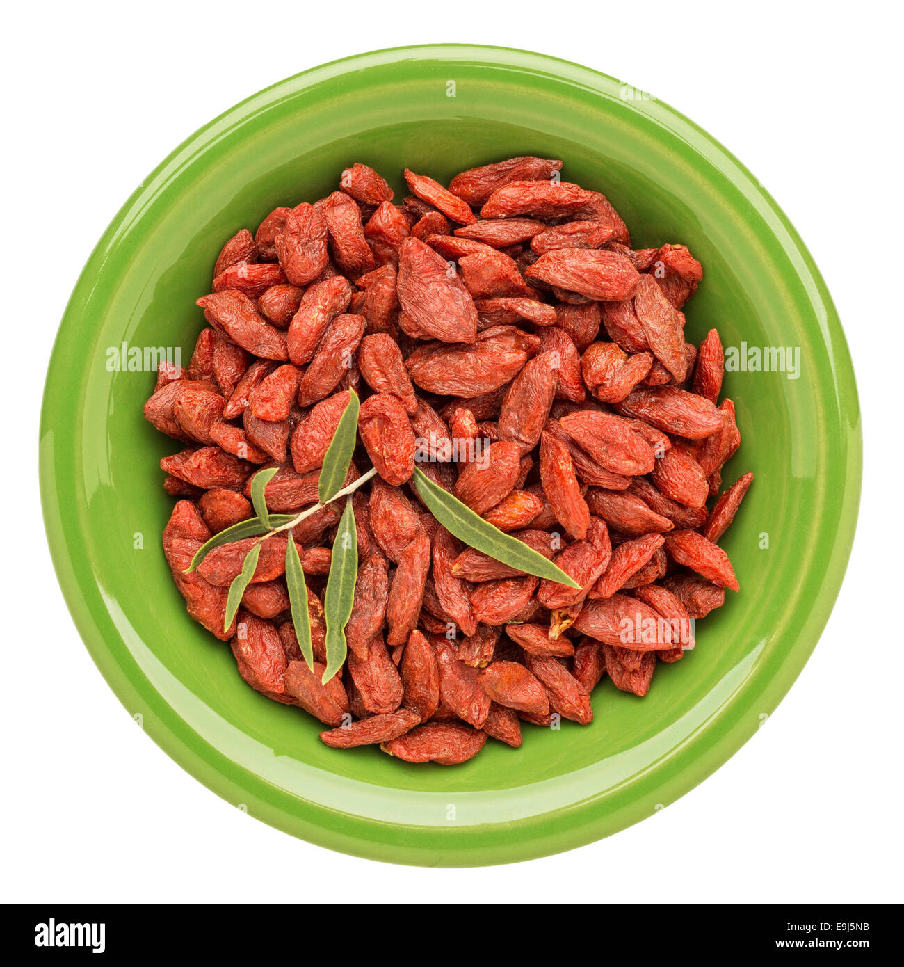 getrocknete Goji-Beeren mit einem frischen Blatt auf eine isolierte grüne Keramikschale Stockfoto