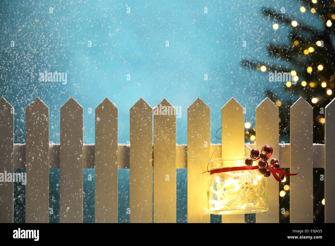 Weihnachtsbeleuchtung in der verschneiten Nacht an Zaun hängen Stockfoto