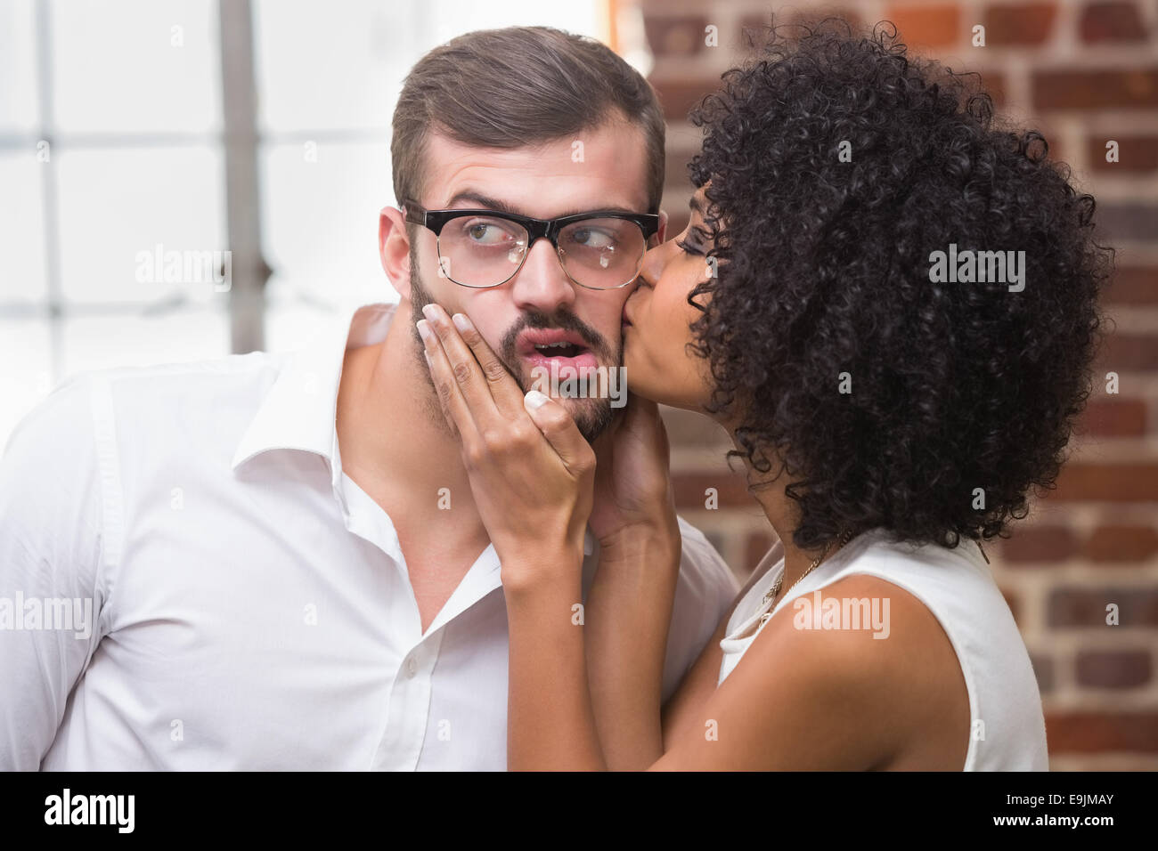Frau küssen Mann im Büro Stockfoto