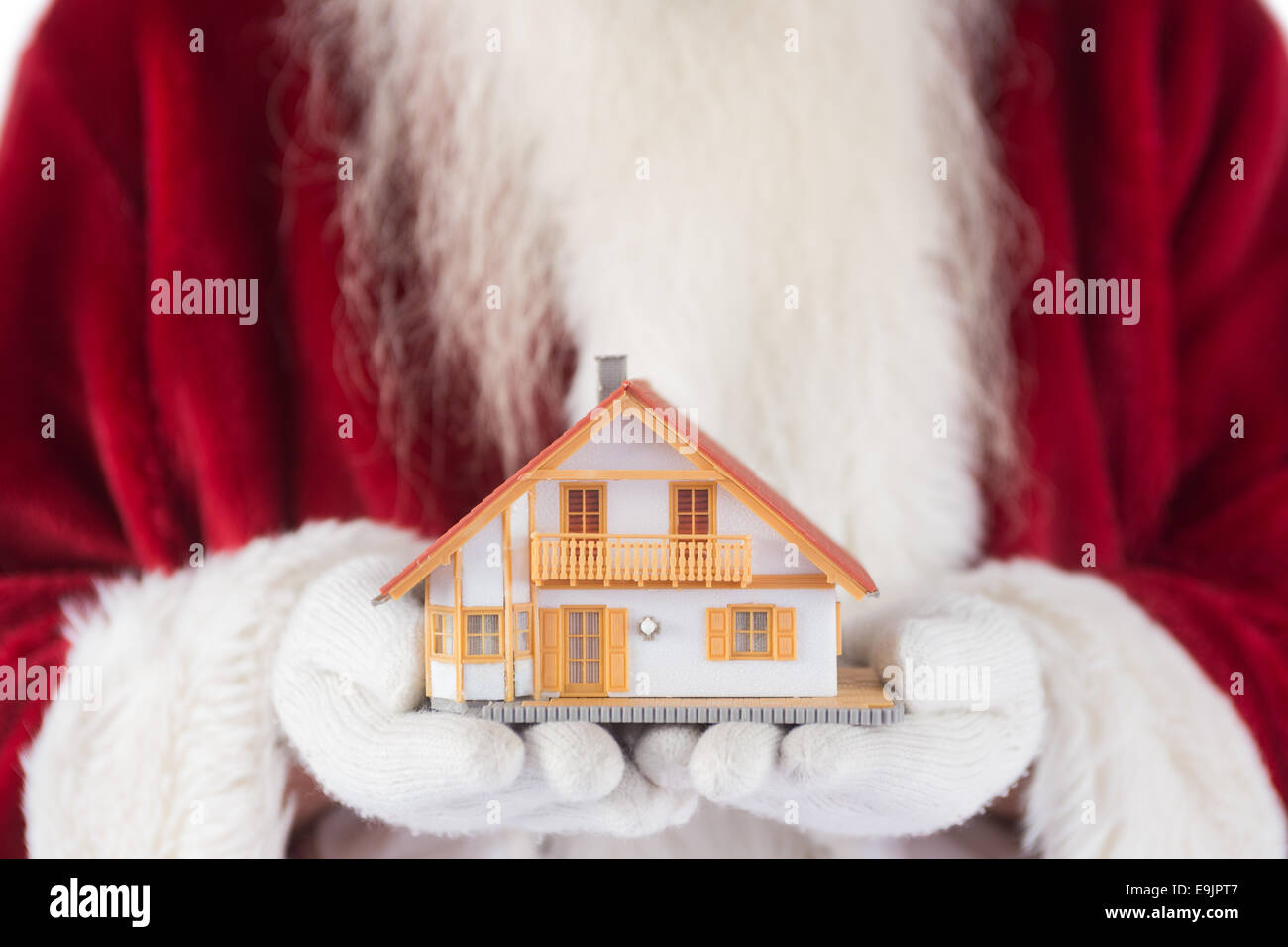 Santa hält ein kleines Haus in seinen Händen Stockfoto