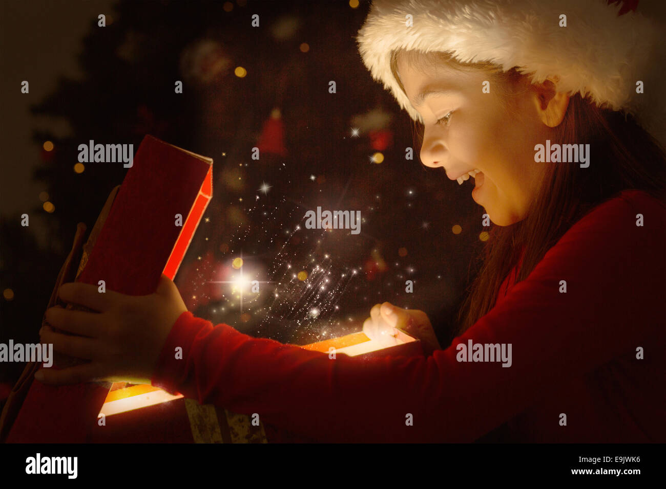 Zusammengesetztes Bild von kleinen Mädchen, die ein magisches Weihnachtsgeschenk öffnen Stockfoto