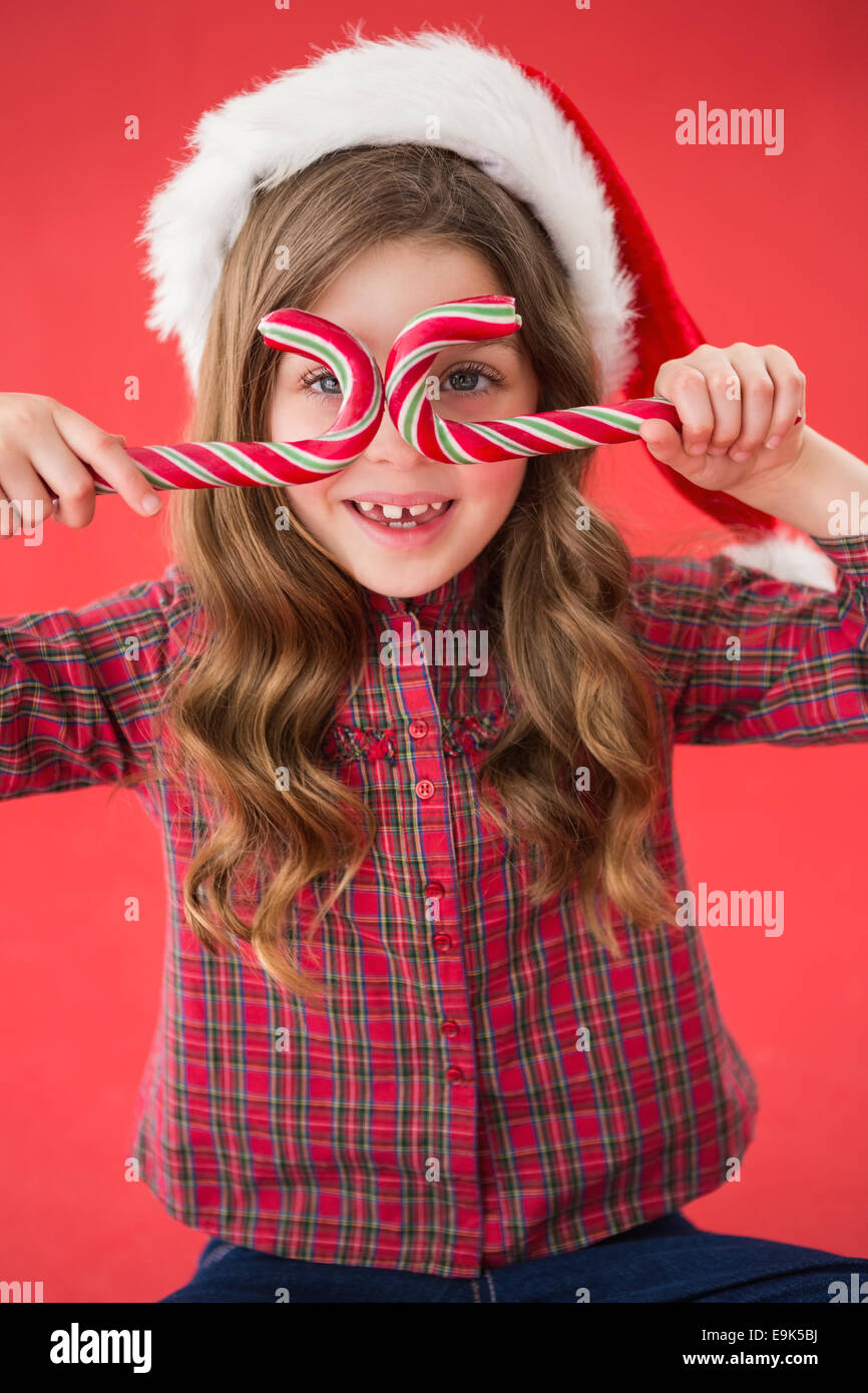 Glückliche kleine Mädchen in Nikolausmütze mit Zuckerstangen Stockfoto