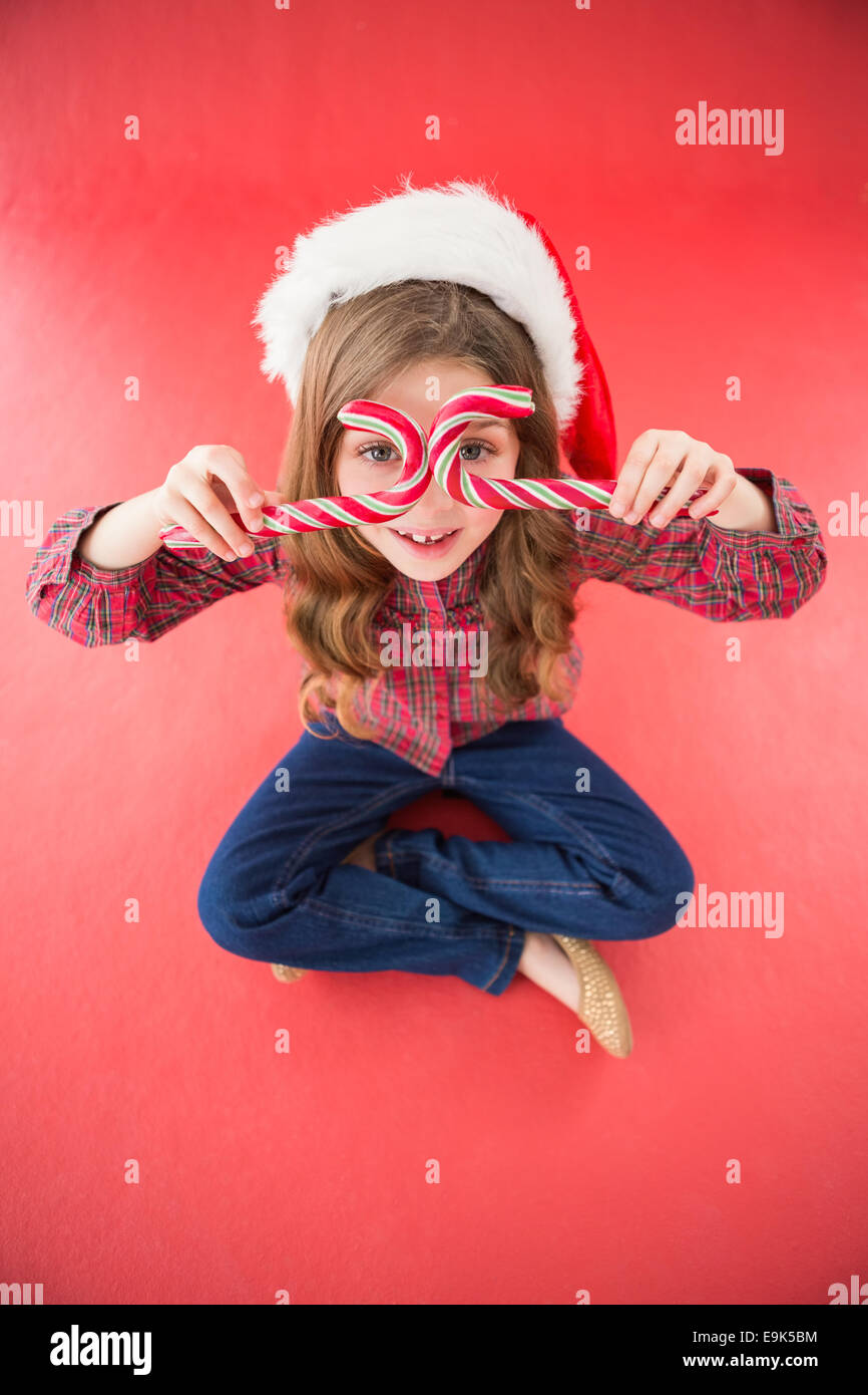 Glückliche kleine Mädchen in Nikolausmütze mit Zuckerstangen Stockfoto