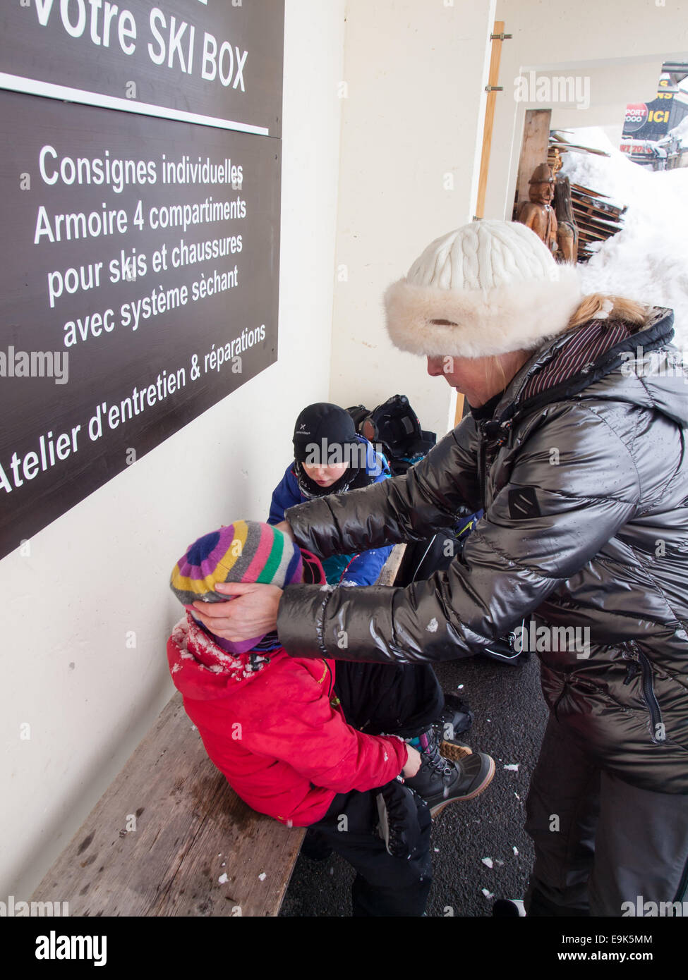 Mutter und kleine Kinder tragen Winterkleidung umziehen nach dem Skifahren Stockfoto