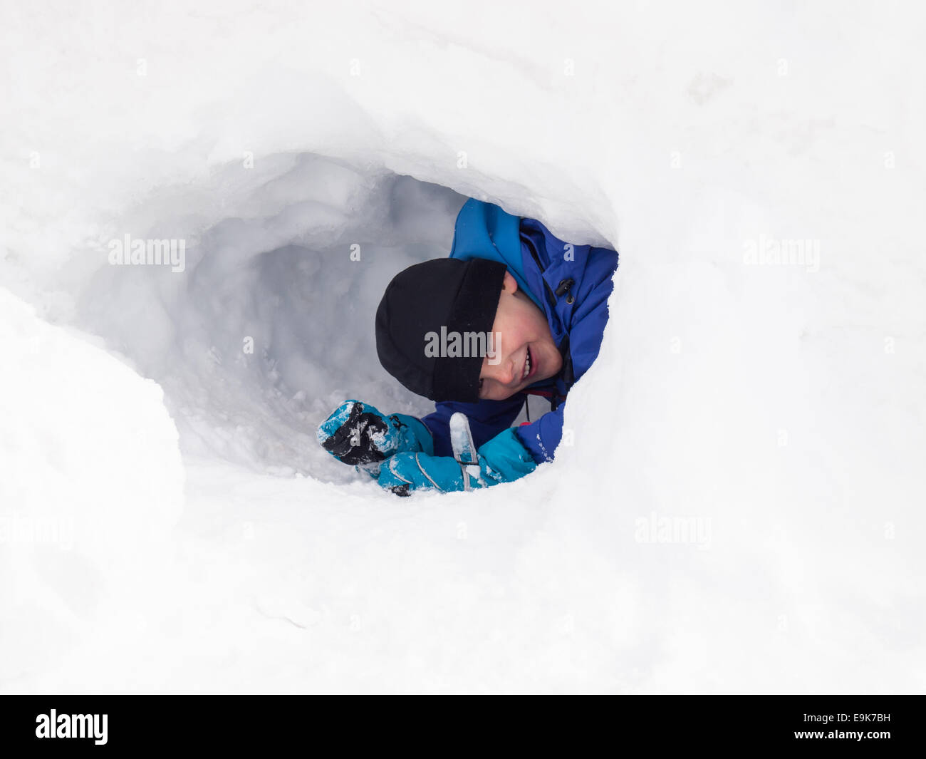 kleinen lächelnden jungen in Winterkleidung in einem Schnee-Loch spielen Stockfoto