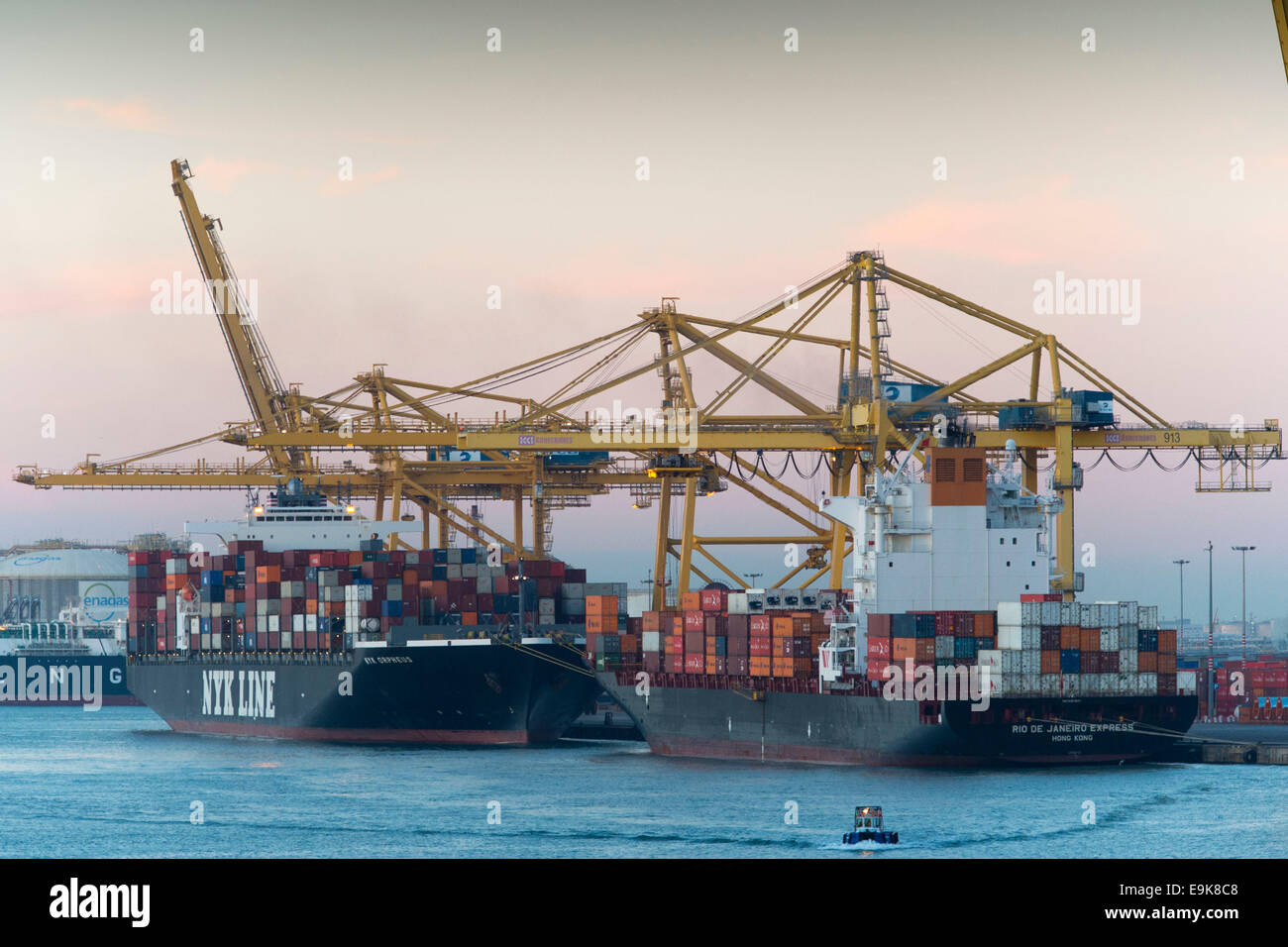 Gelben Kräne bewegen Versandbehälter an Barcelonas Hafen - Port de Barcelona - bei Sonnenaufgang. Stockfoto