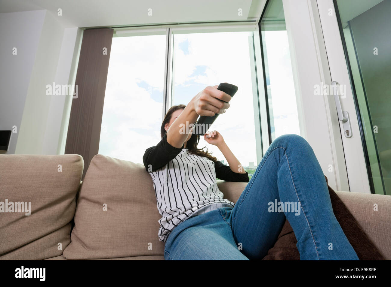 Frau Senderwechsel beim Fernsehen zu Hause auf sofa Stockfoto